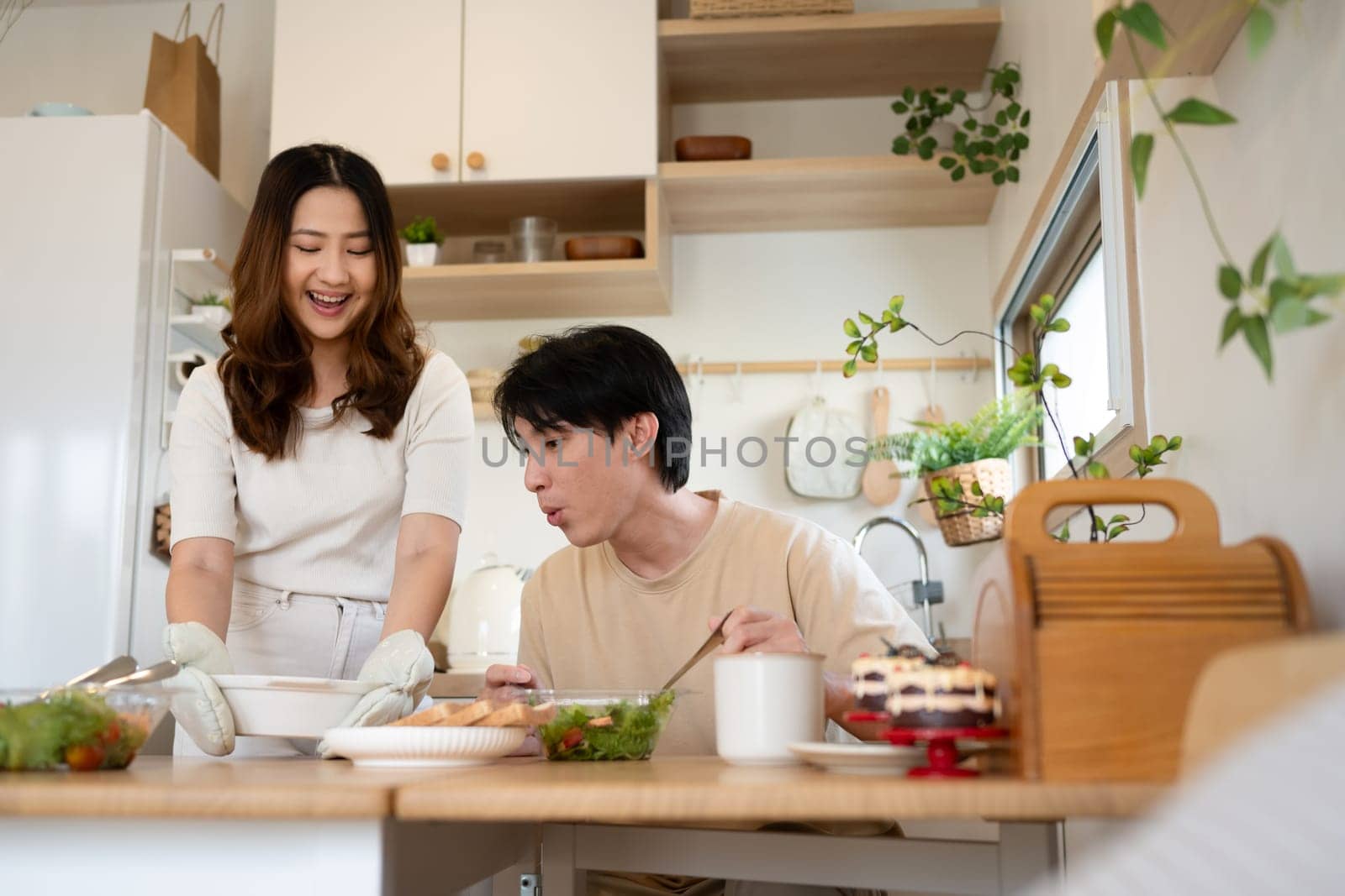 Young asian woman serving healthy lunch to her husband in a minimalist kitchen.