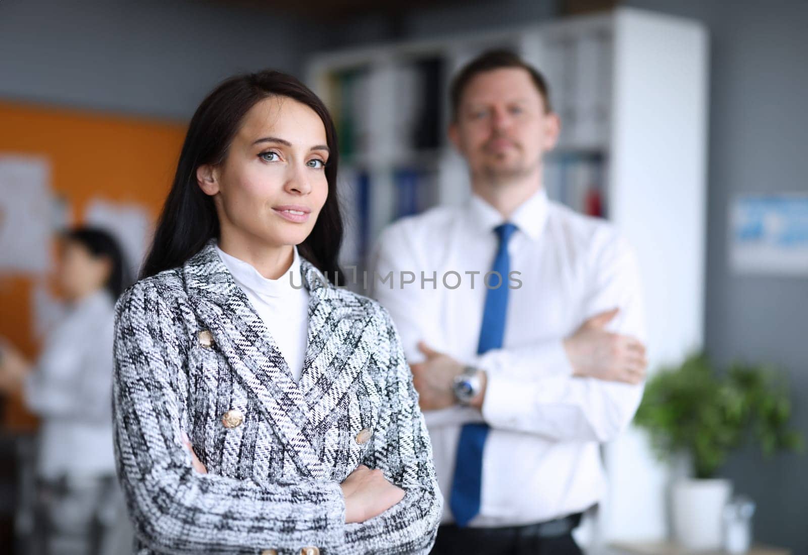 Portrait of businesswoman in stylish trendy costume posing in company office. Smiling beautiful worker and male partner. Successful business and co-workers concept