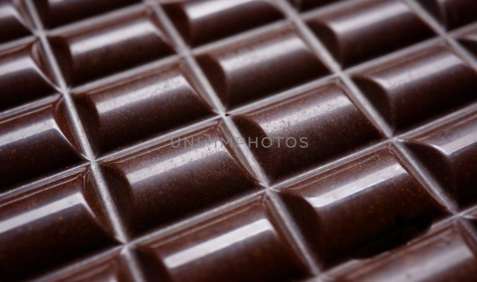 Close-up of chocolate bar without foil. Milk dessert perfect for tea or coffee break. Appetizing food for happiness. Nutrition and calories. Unhealthy snack concept