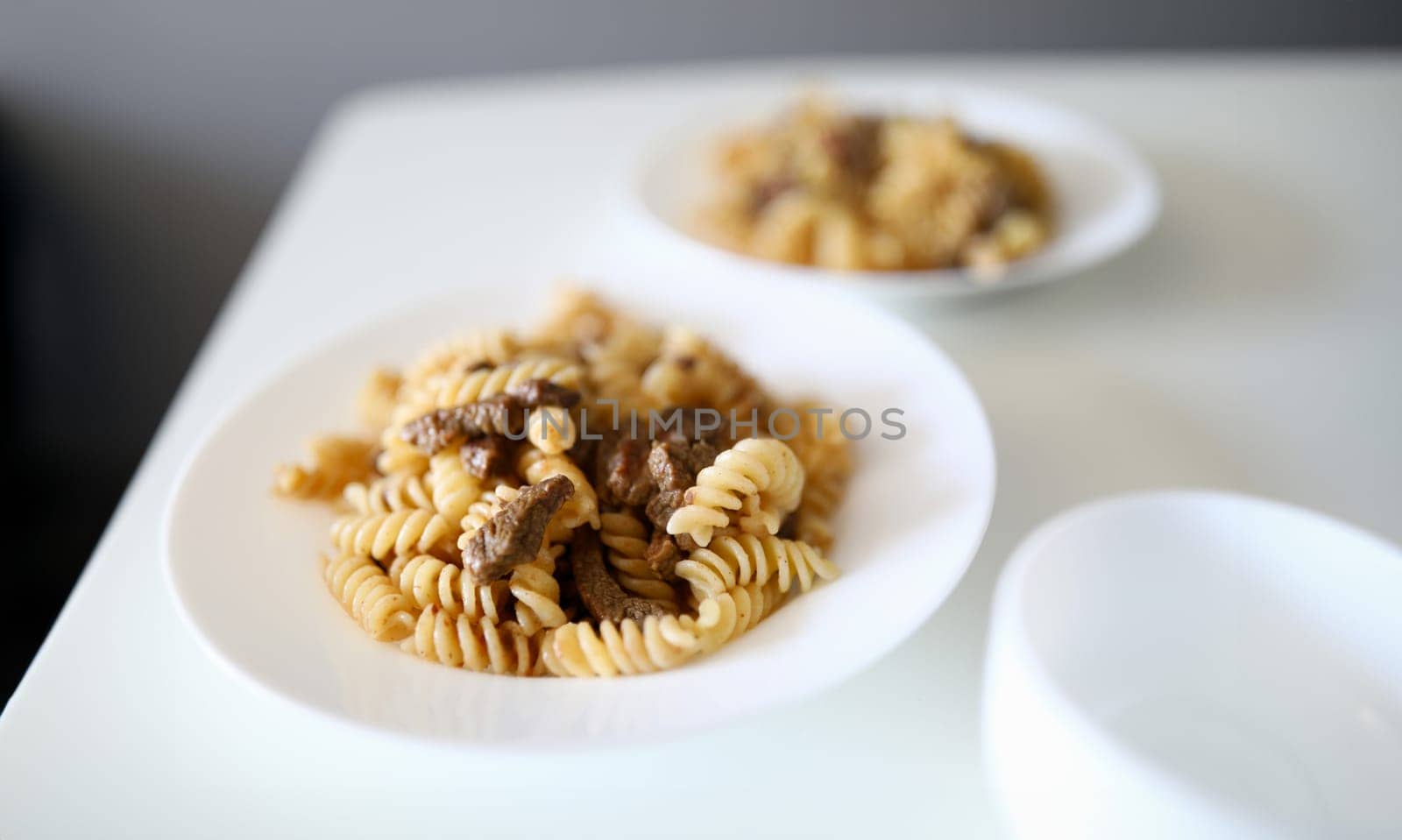 Close-up of traditional italian pasta bolognese served on white plate. Delicious meal for dinner. Portion for two people. Healthy and yummy food concept