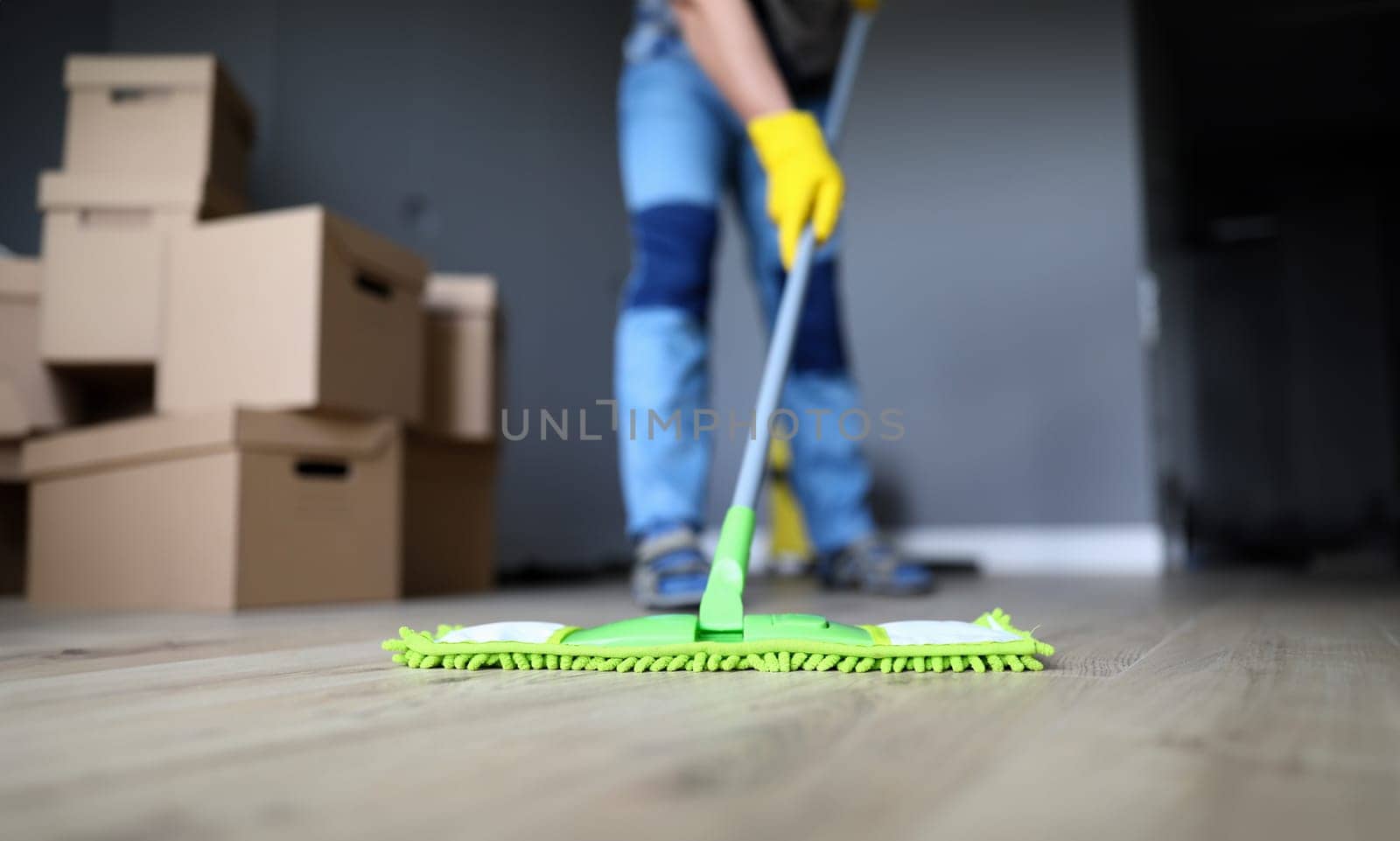 Close-up of male hands holding microfiber fluffy rag and mopping floors. Cleaning apartment after moving or renovation. Housework and spring-cleaning concept
