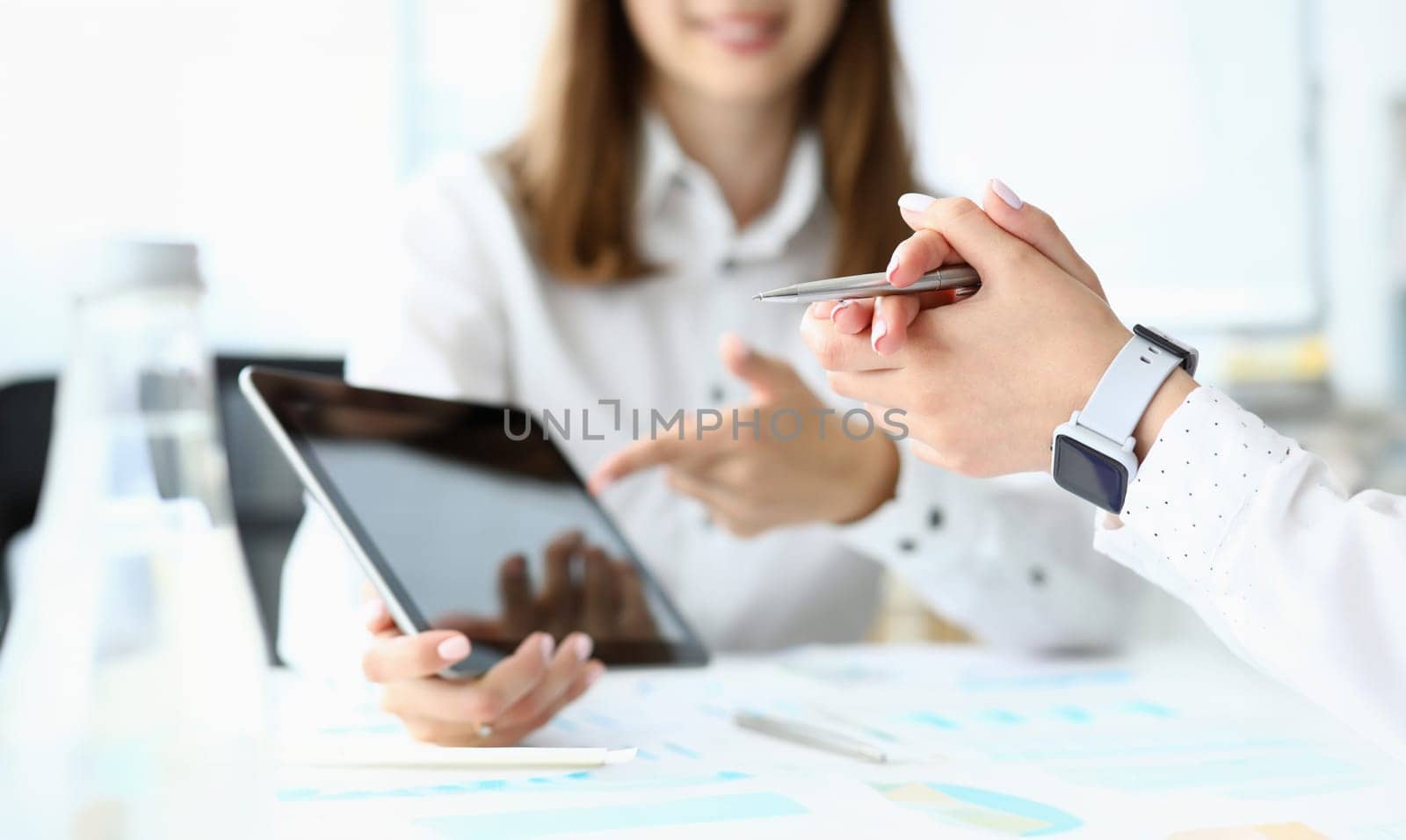Focus on tender female hands holding pen. Manager demonstrating something on modern tablet with empty copy space. Smart businesspeople discussing something important. Business meeting concept
