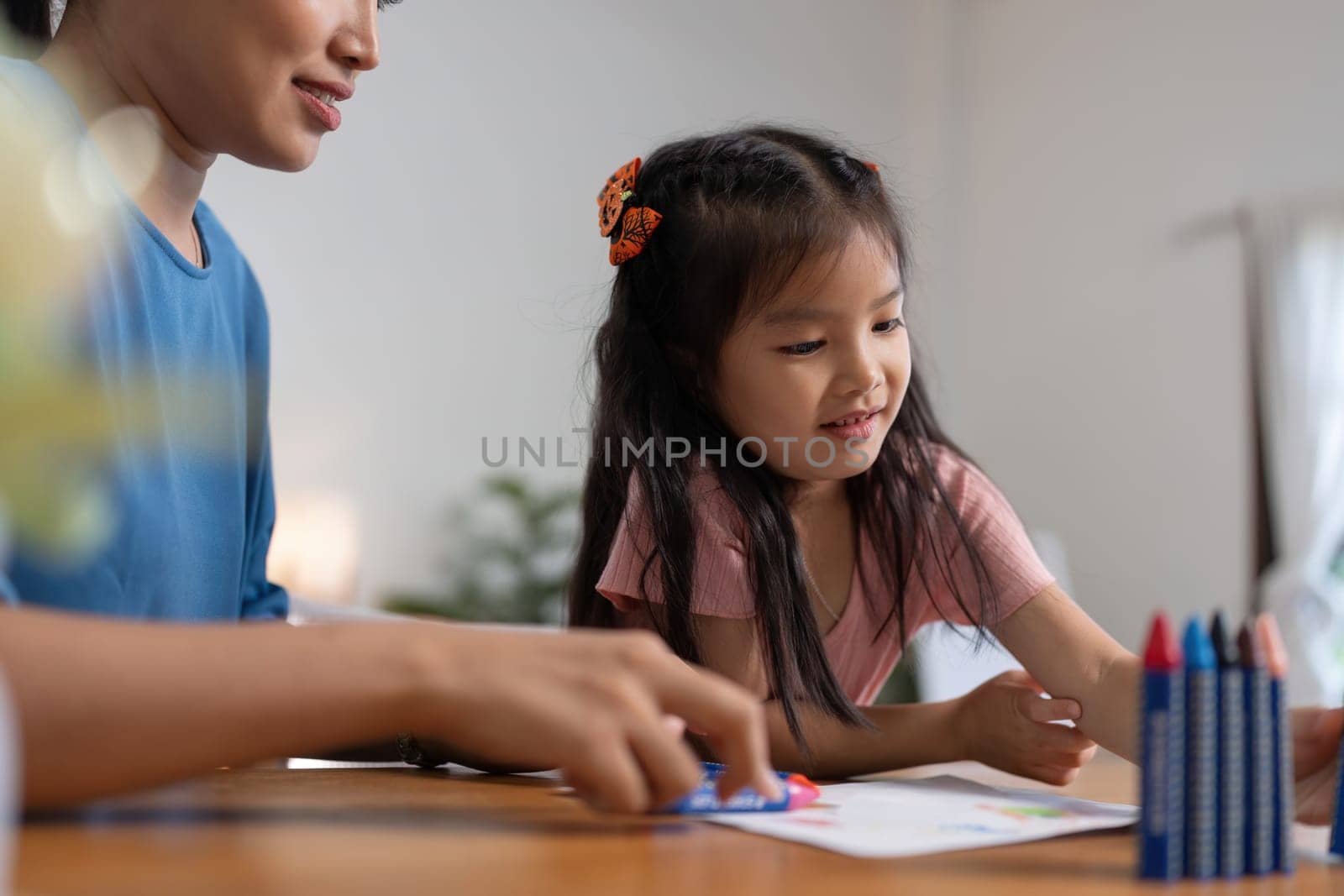 Happy family mother and daughter study or draw together at home in living room.