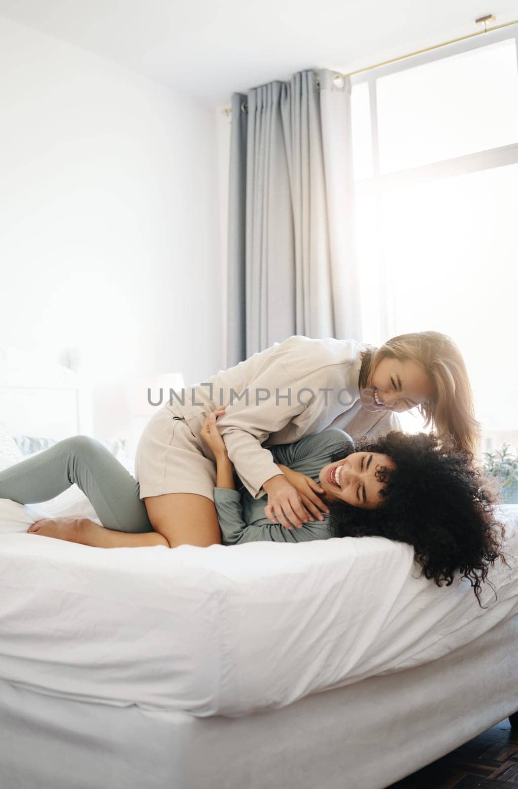 Happy, laughing and a lesbian couple in the bedroom in the morning for love and bonding. House, romance and gay or lgbt women on a bed for conversation, tickle and comfortable in home together by YuriArcurs