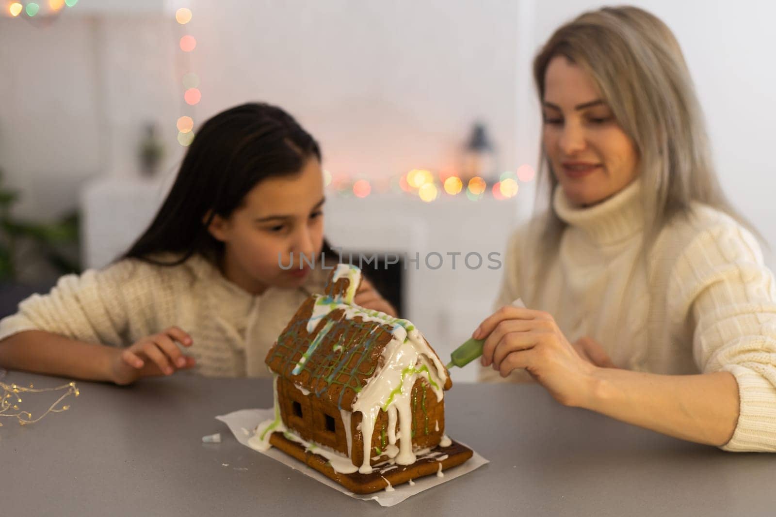 Family decorating gingerbread house on Christmas eve by Andelov13