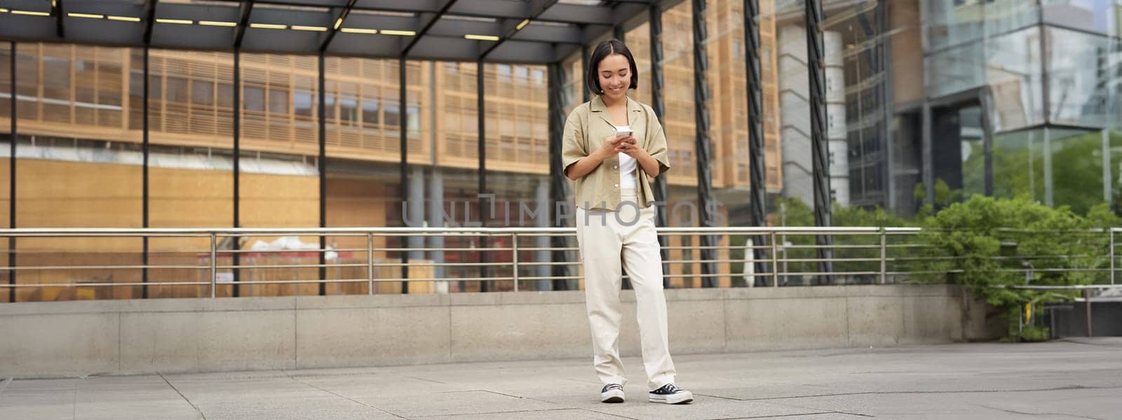 Portrait of asian female model with telephone. Young korean girl holding smartphone on street, using telephone.