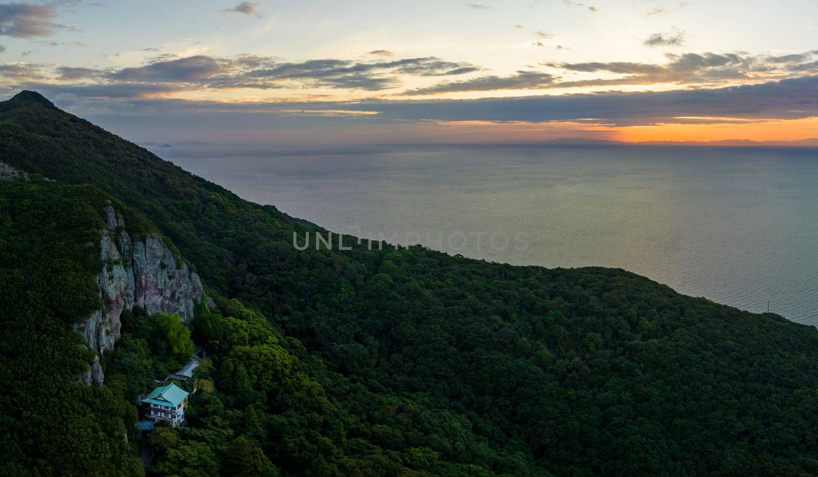 Aerial panoramic view of remote temple on mountain by sea at sunrise by Osaze