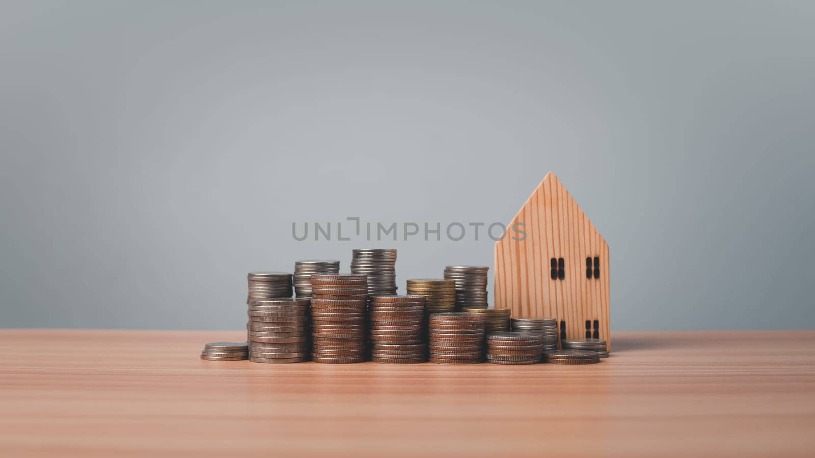 Model wooden house and coins lined up on wooden floor on white background. Concepts of finance, savings and investment. Real estate concepts. by Unimages2527
