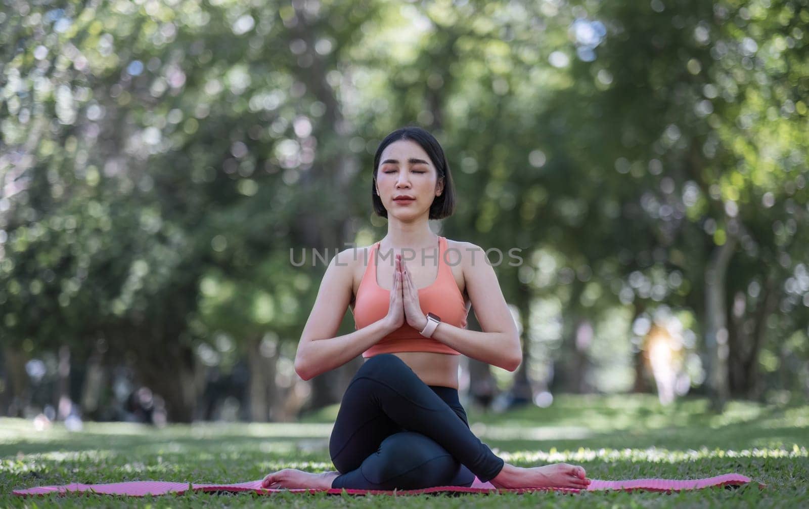 Attractive and charming Asian woman in her 30s in sportswear doing yoga poses, relaxing muscles. Asian woman practicing yoga in a beautiful green park by wichayada