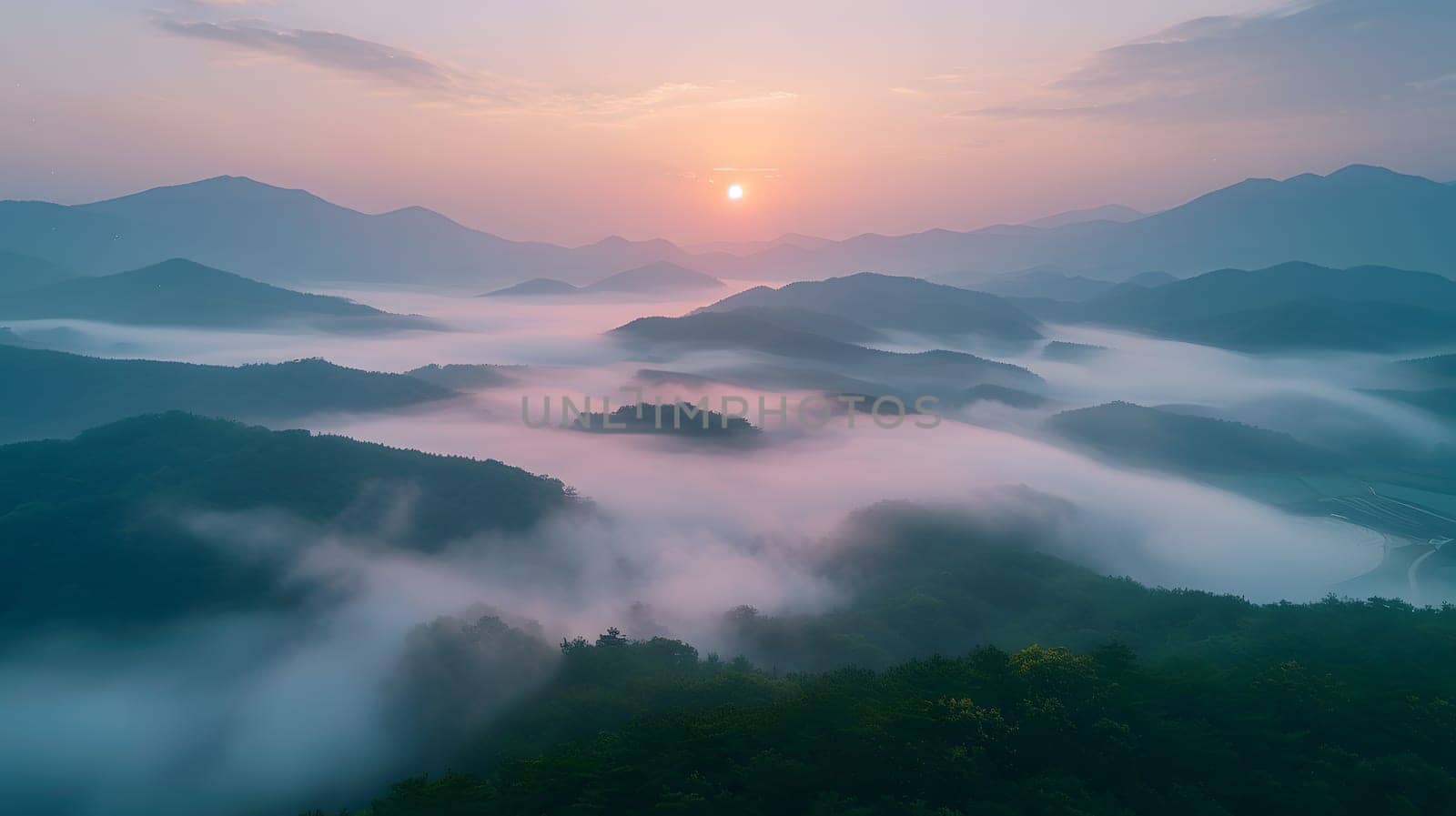 A breathtaking aerial view of a foggy mountain range at sunset with clouds hanging low in the sky, creating a mystical atmosphere. The water reflects the afterglow of dusk on the horizon
