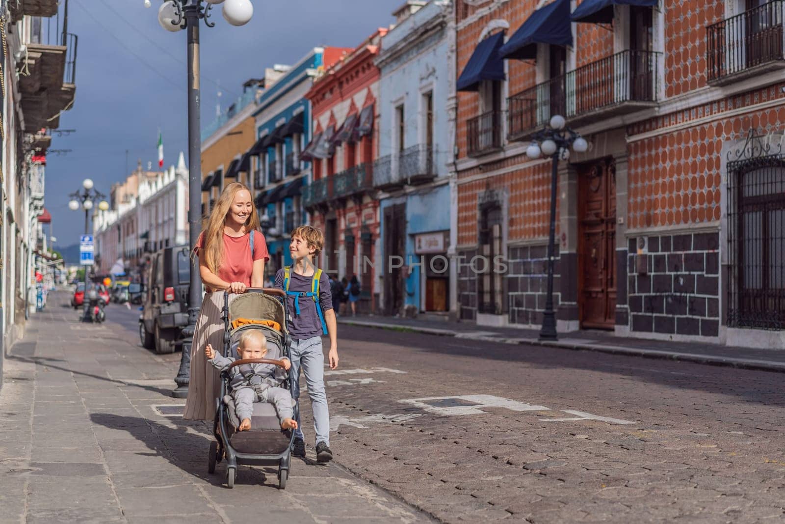 Mother tourist with her toddler and teenage sons walking through the colorful colonial streets of Puebla, Mexico. Travel, cultural exploration, and vibrant architecture concept.