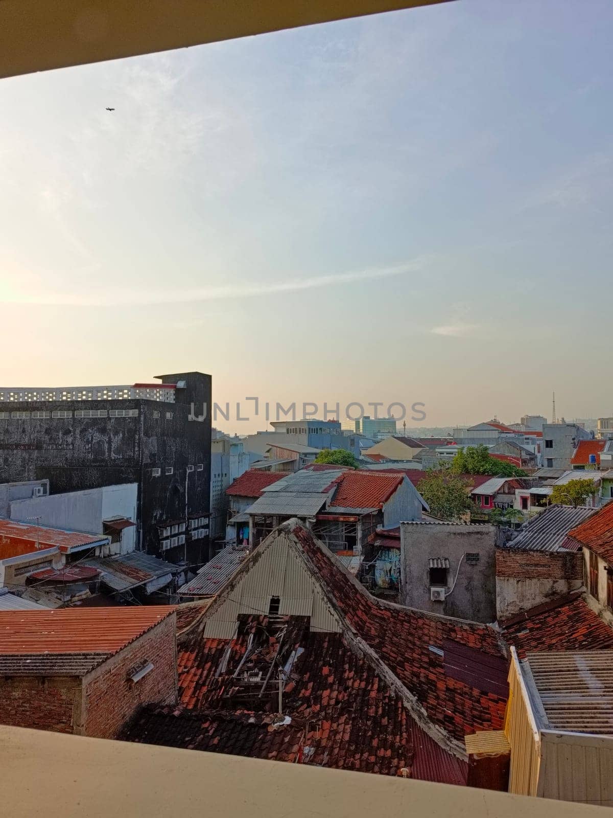 An aerial perspective showcasing the variety of roofing styles in a densely populated urban area under a clear blue sky, highlighting architectural diversity and city life.