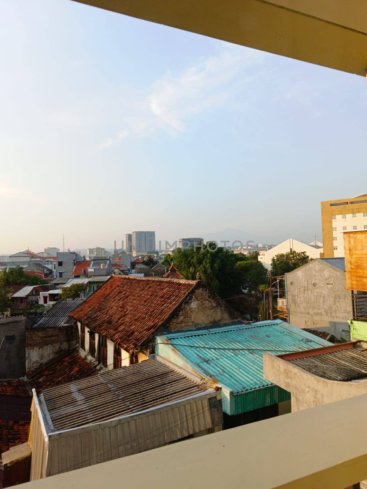 An aerial perspective showcasing the variety of roofing styles in a densely populated urban area under a clear blue sky, highlighting architectural diversity and city life.