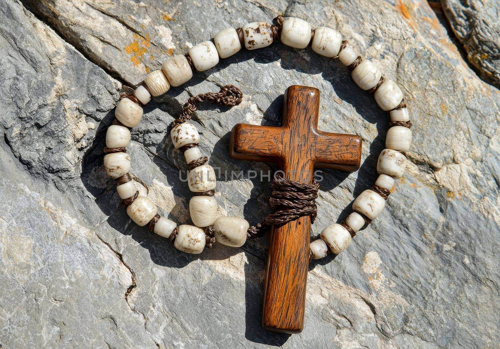 Old wooden Franciscan rosary, on the large Christian cross Jesus on a stone background, religious and faith concept..