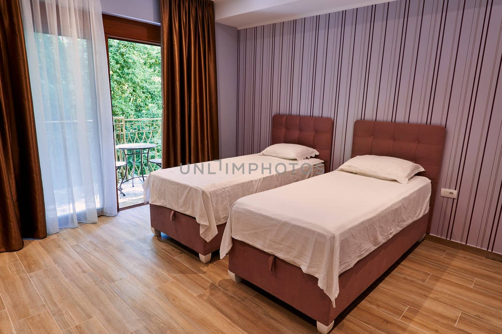 Two single beds in a hotel room near a panoramic window. High quality photo
