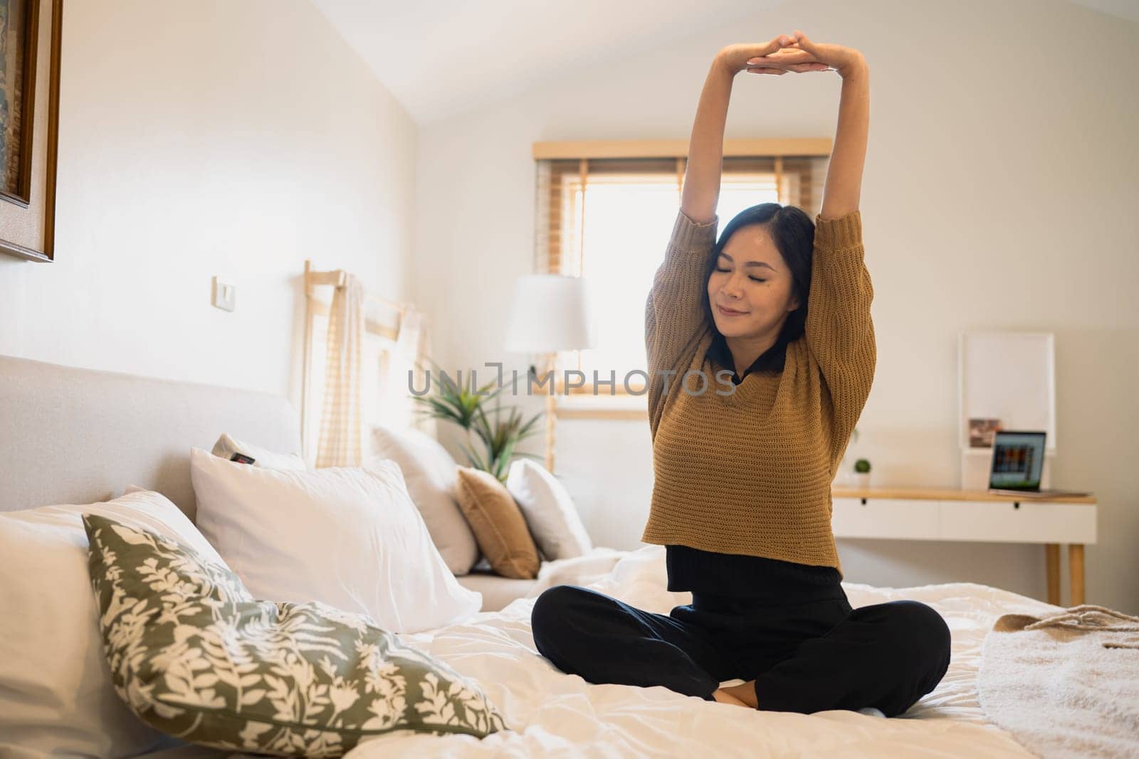 Carefree young woman stretching on bed and preparing for the day.