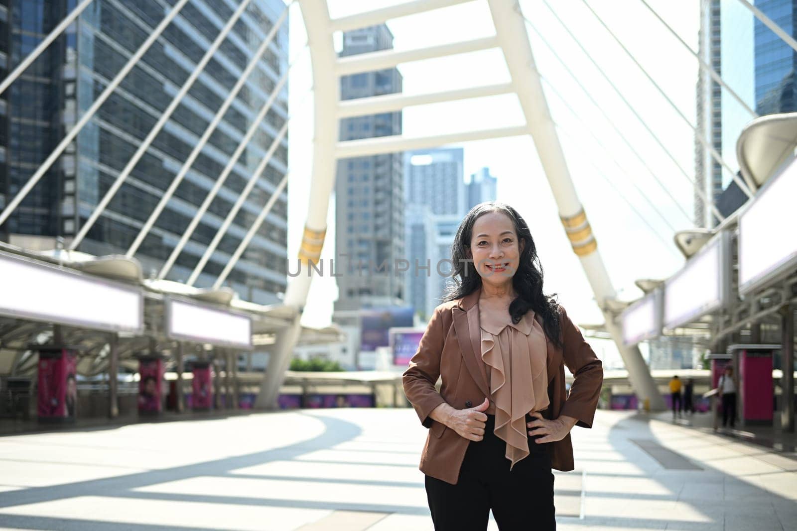 Confident mature businesswoman posing in modern cityscape.