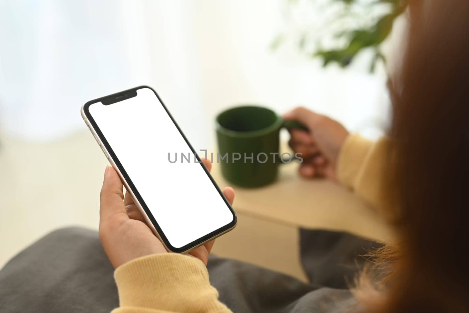 Close up of woman relaxing and holding smartphone with blank display.