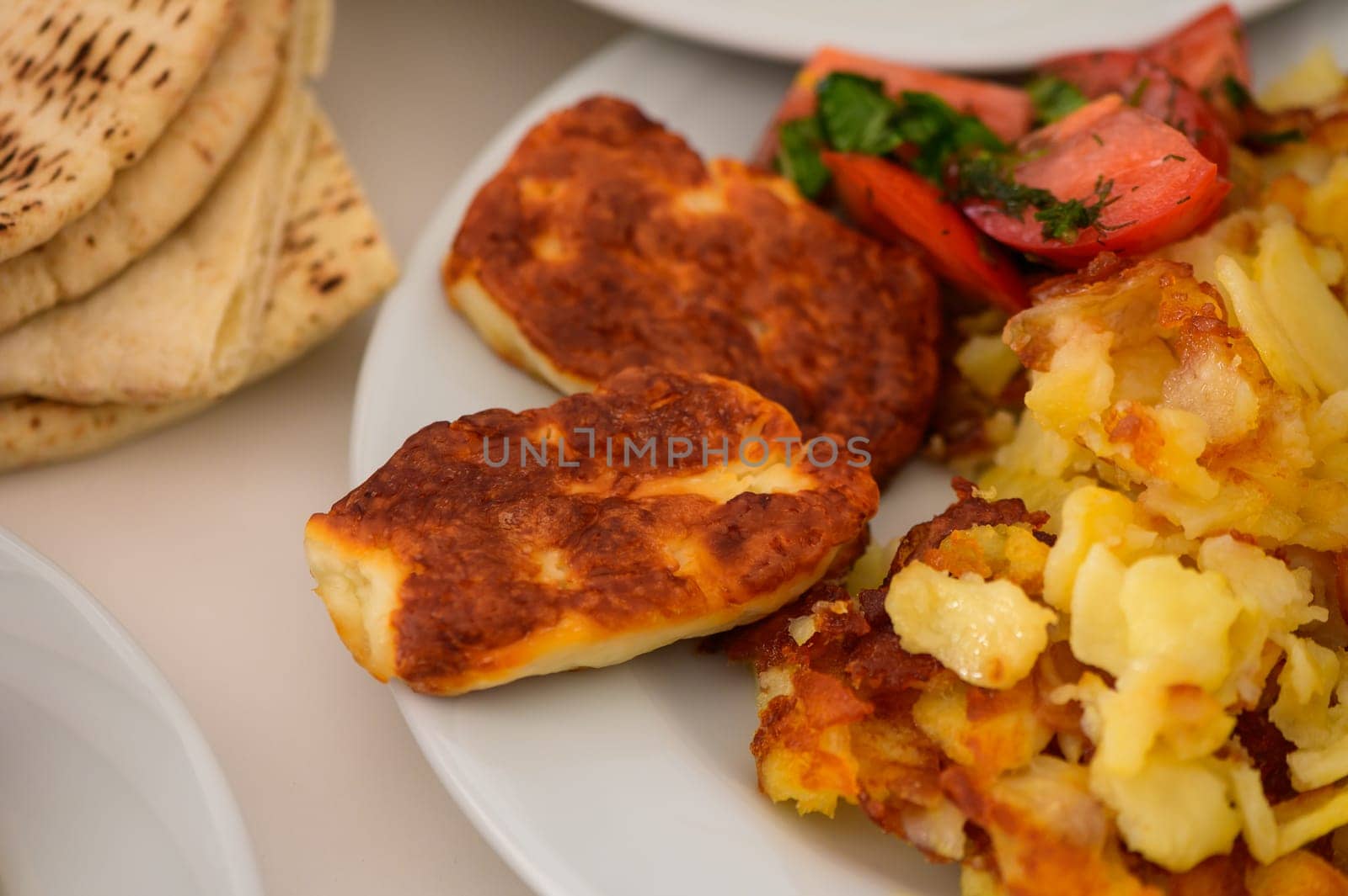 A delicious platter featuring grilled cheese, roasted vegetables, and bread, perfect for a sunny lunch outdoors.