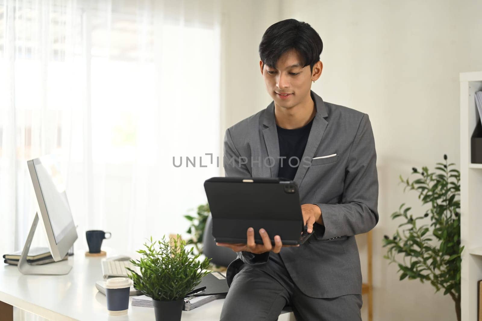 Focused young entrepreneur reviewing information on digital tablet in his office.