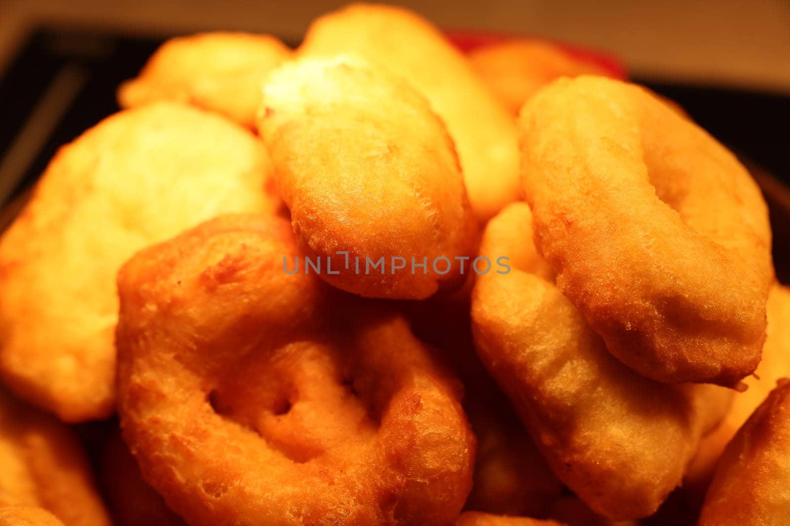 A delightful and tempting stack of freshly fried, golden doughnuts that are fluffy, perfect for any sweet tooth craving