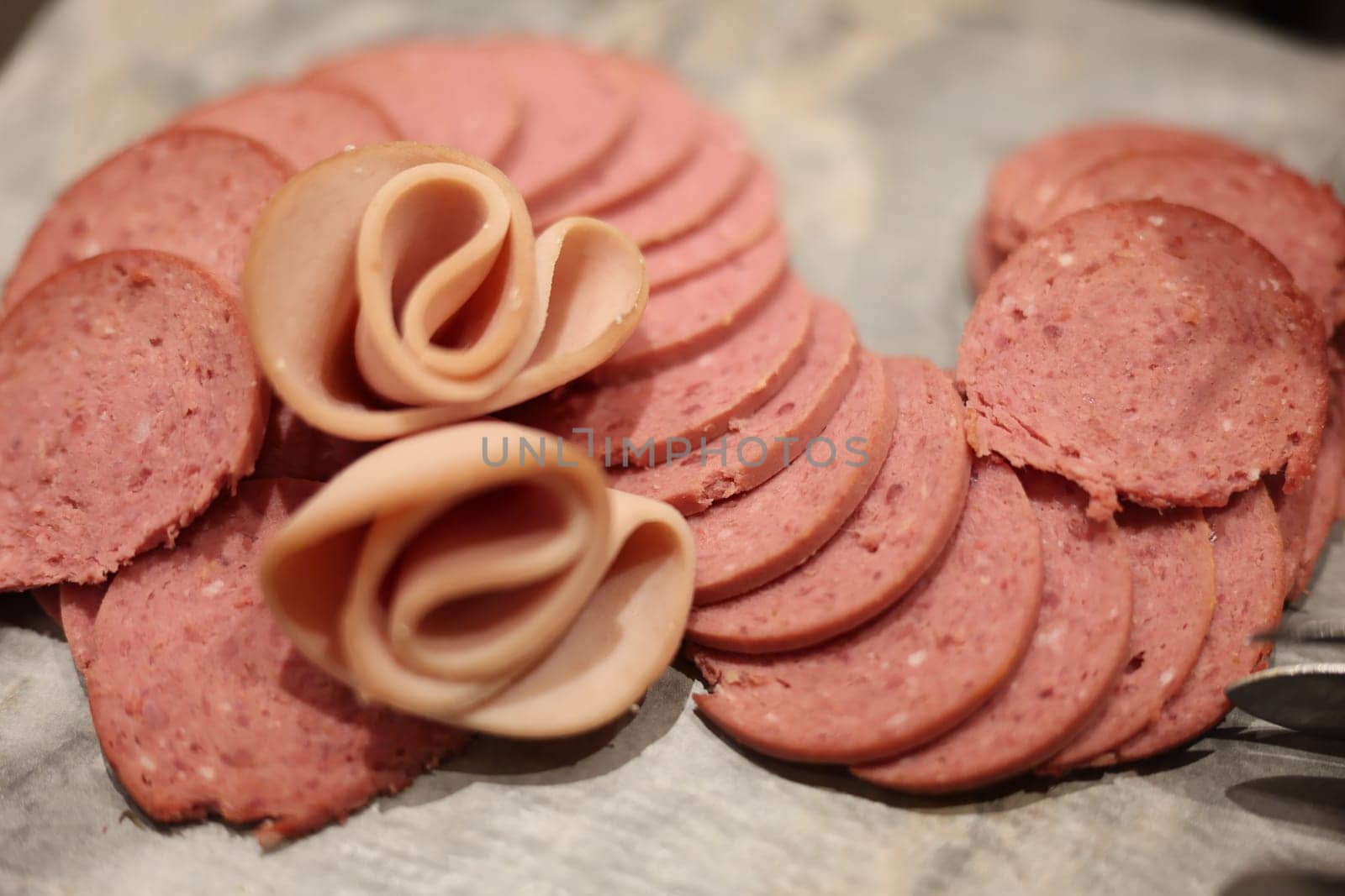 An elegantly artistic arrangement of various deli meats with decorative folds, perfect for fancy charcuterie boards