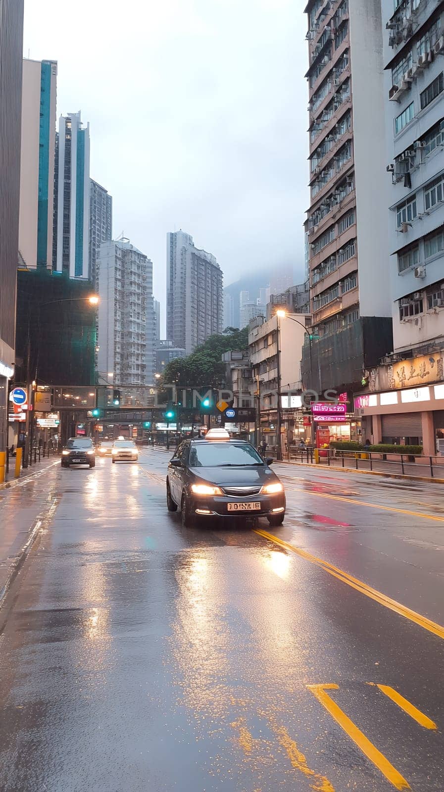 A rainy city street at dusk with wet pavement reflecting lights and a taxi driving by.