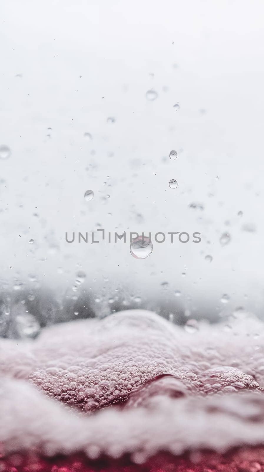 Raindrops fall onto a surface of red bubbling liquid, creating an intriguing mix of movement and detail.
