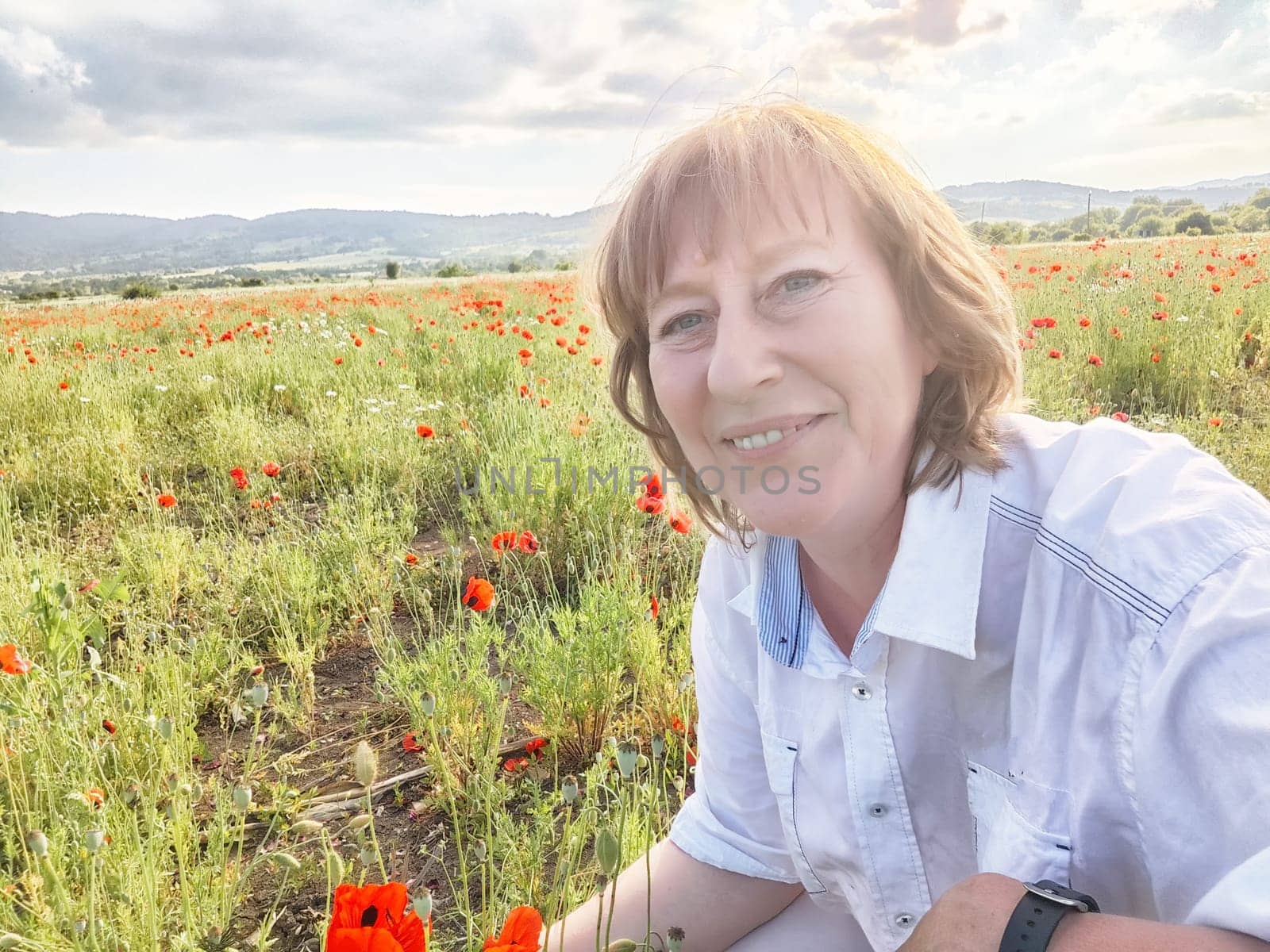 A happy girl in a poppy field. The journey of a middle-aged woman in summer. A tourist on trip