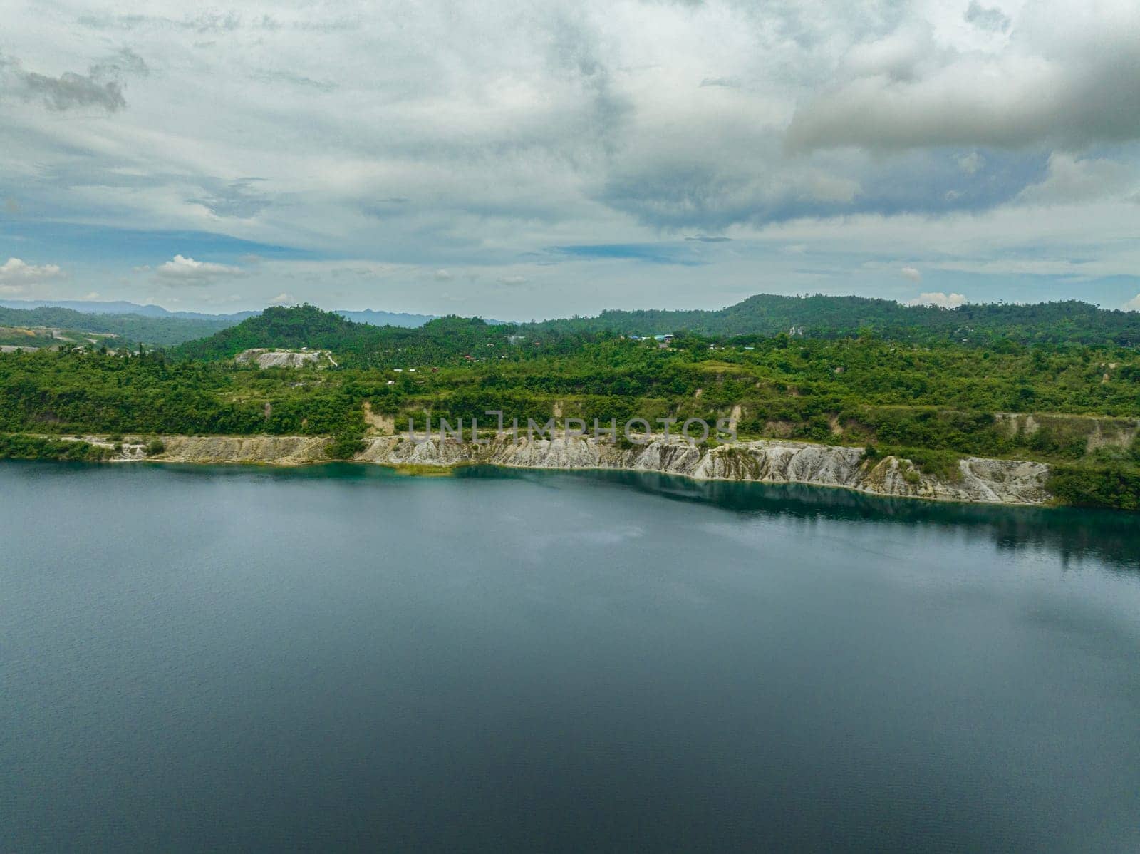 Aerial drone of mining quarry with flooded bottom. Lake with blue water near sand pit. Sipalay, Negros, Philippines.