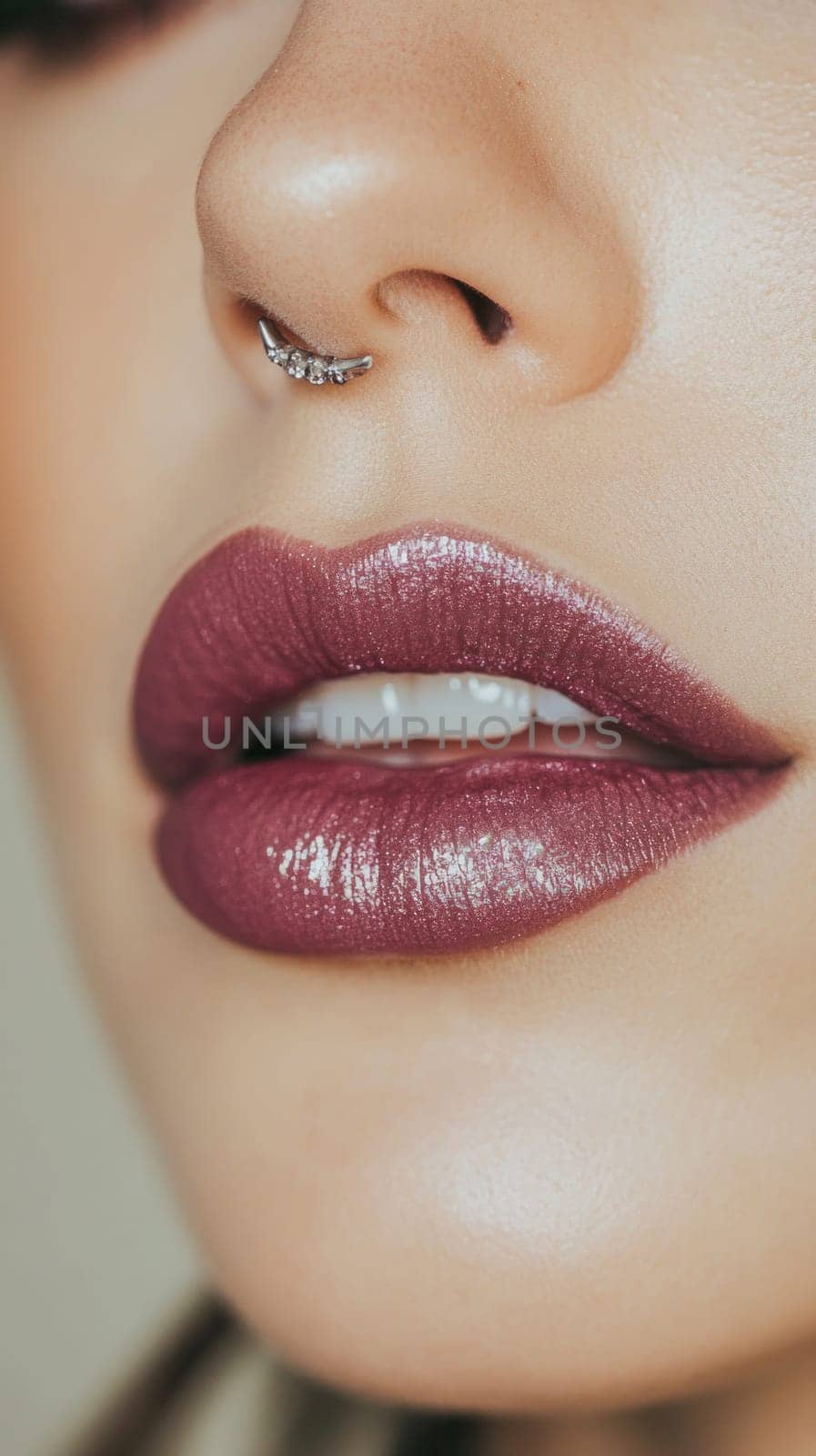 Close-up of a woman's face with septum piercing and glossy dark pink lipstick