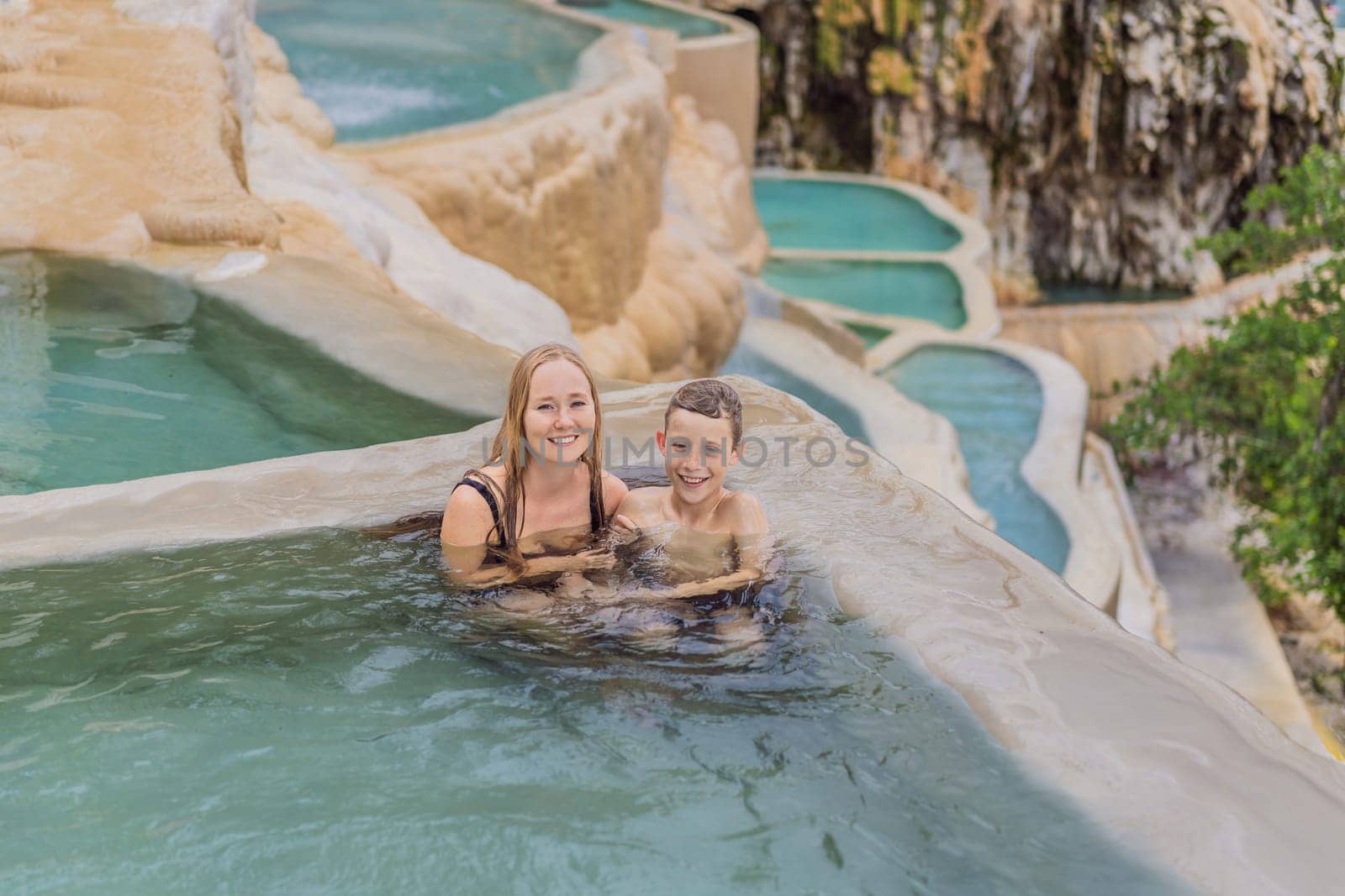 Mother with her toddler and teenage sons bathing in the hot springs of Grutas Tolantongo, Mexico. Family adventure, relaxation, and natural wellness concept.