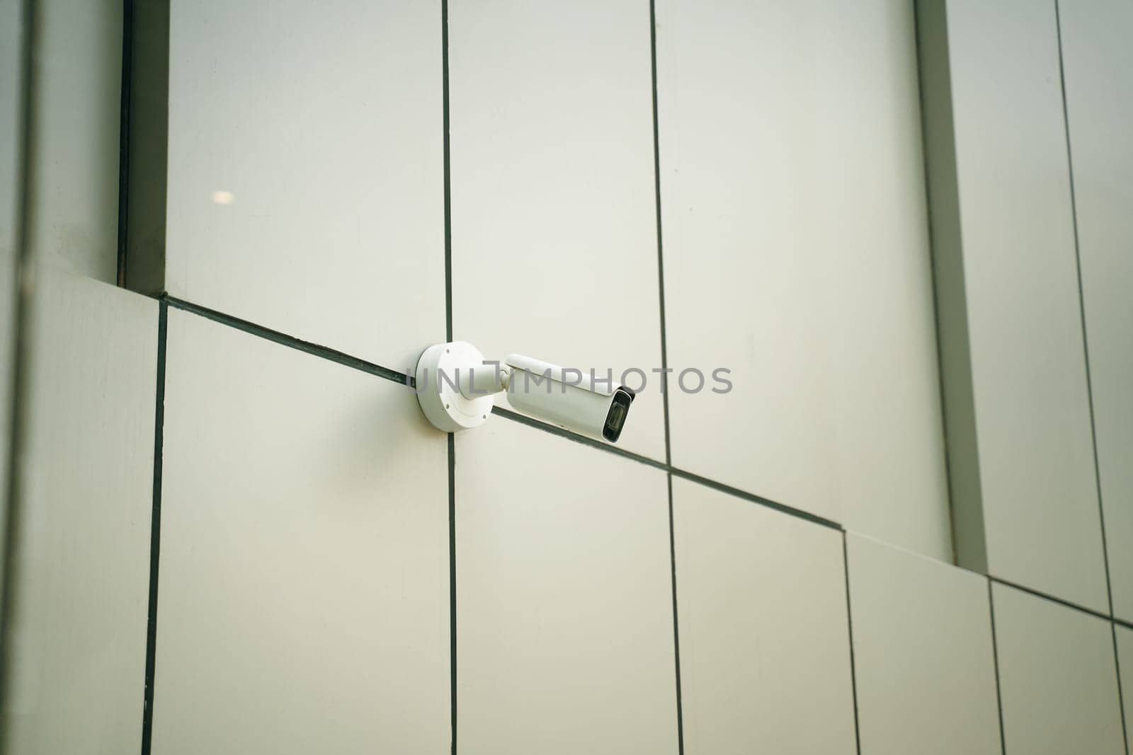 A sleek, modern surveillance camera has been installed on the exterior facade of a contemporary building design