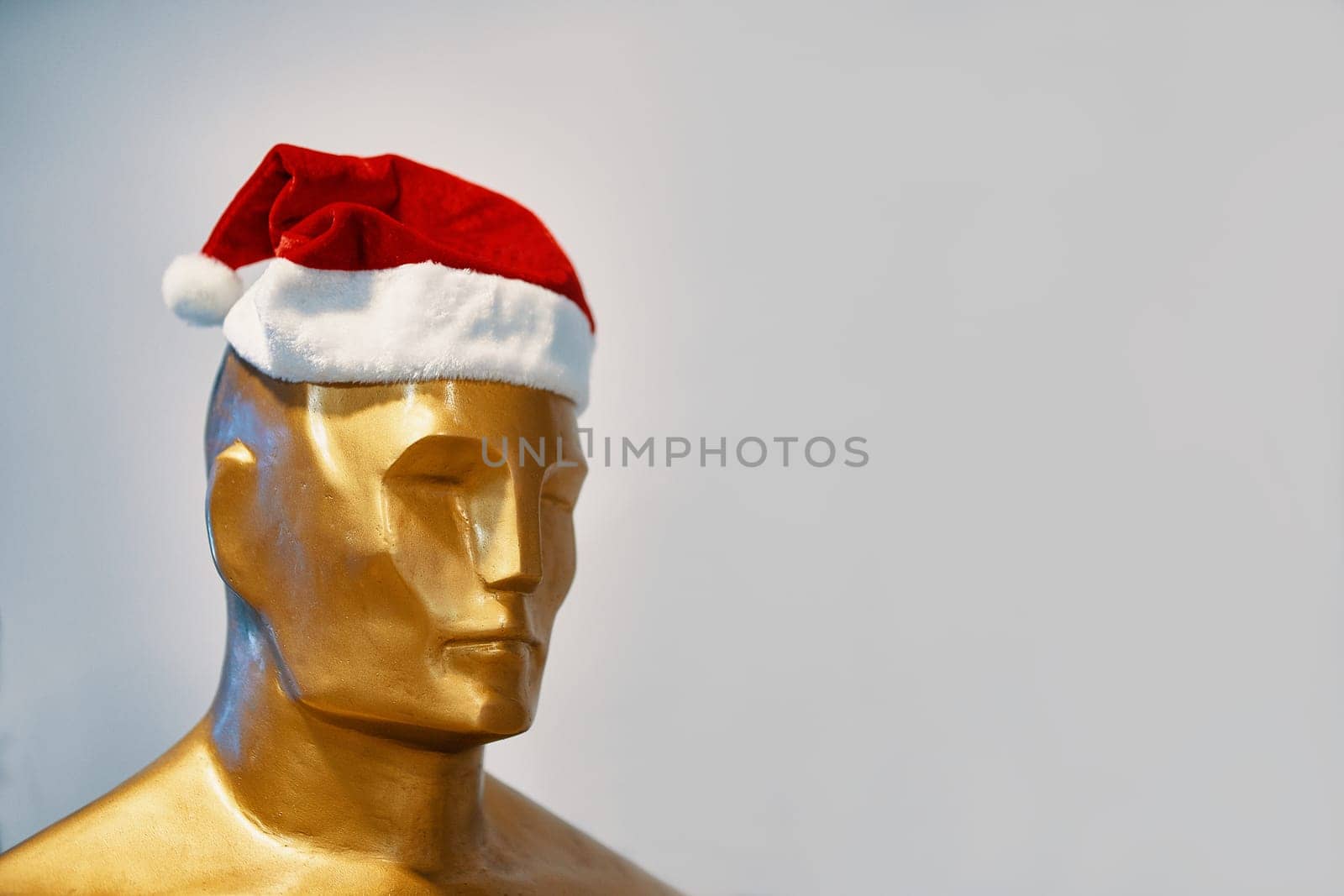 Bishkek, Kyrgyzstan - December 21, 2018: The man in the Christmas hat. A Golden statue of Oscar stands in a Christmas hat.
