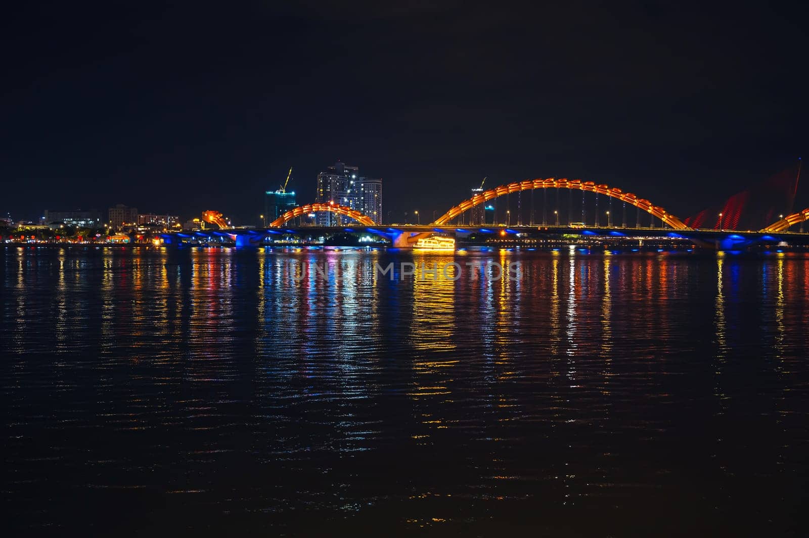 Panorama of Dragon Bridge or Cau Rong Bridge over the Han River in Da Nang in Vietnam at night with a golden backlight