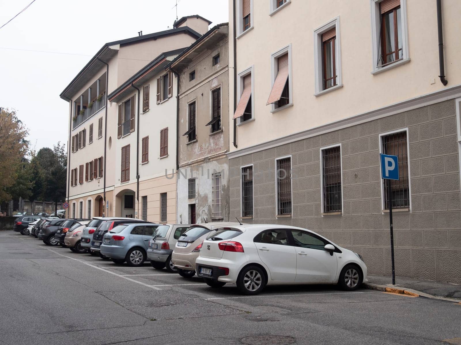 Cremona, Lombardy, Italy October 15th 2024 White car is parking near a parking sign in a residential area with apartment buildings and other parked cars
