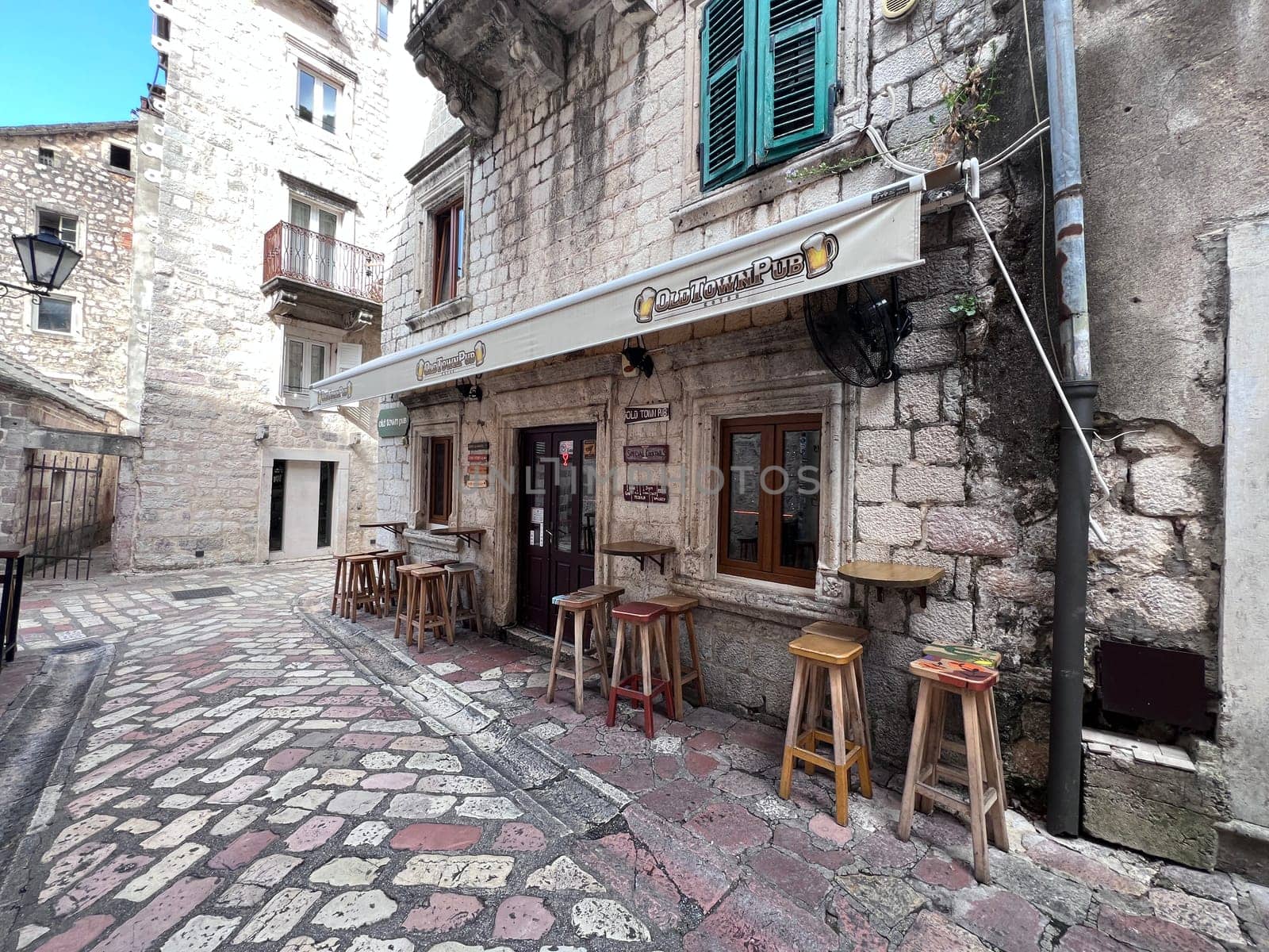 Kotor, Montenegro September 18th 2024: A pub on a square in the old town of Kotor, with flying umbrellas in the background, Montenegro, no people. High quality photo