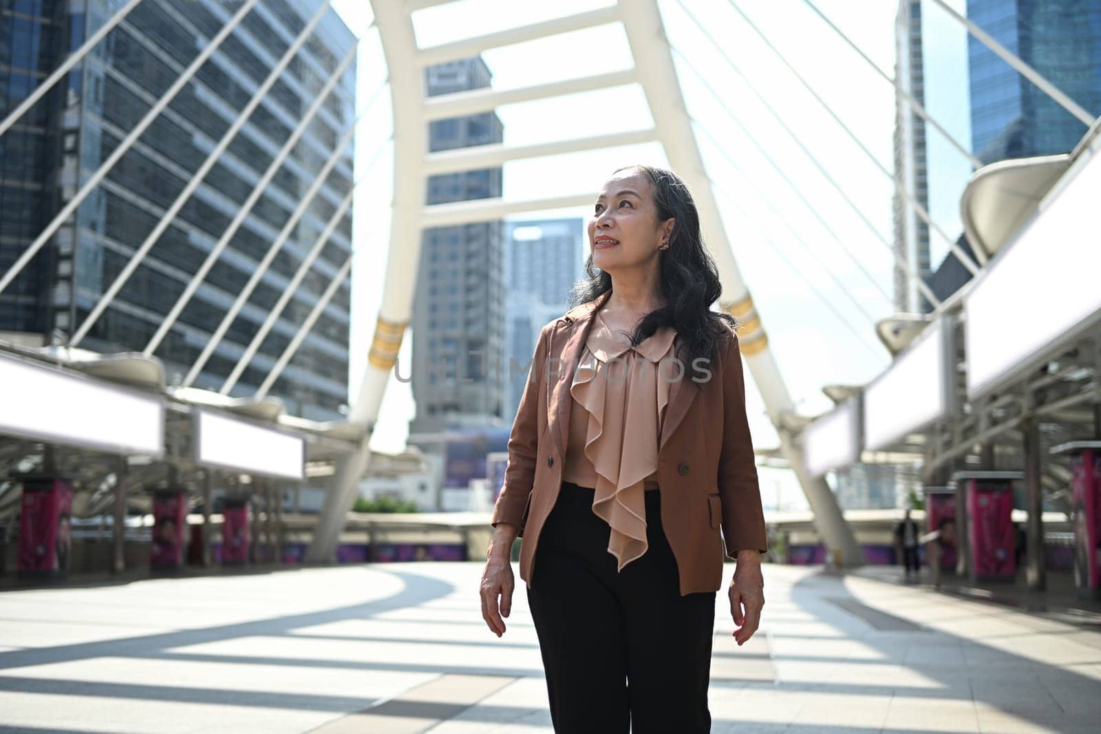Elegant middle aged businesswoman in stylish suit walking through downtown.