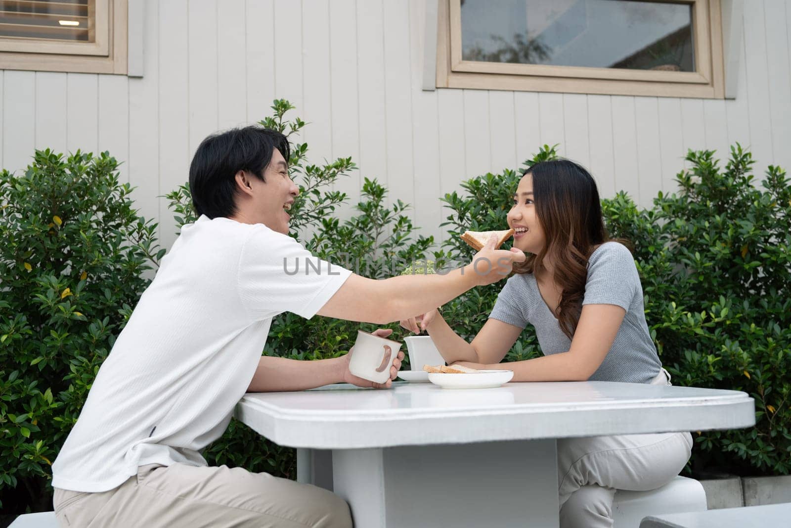 Loving asian couple sharing a breakfast and enjoying relaxed outdoor together.