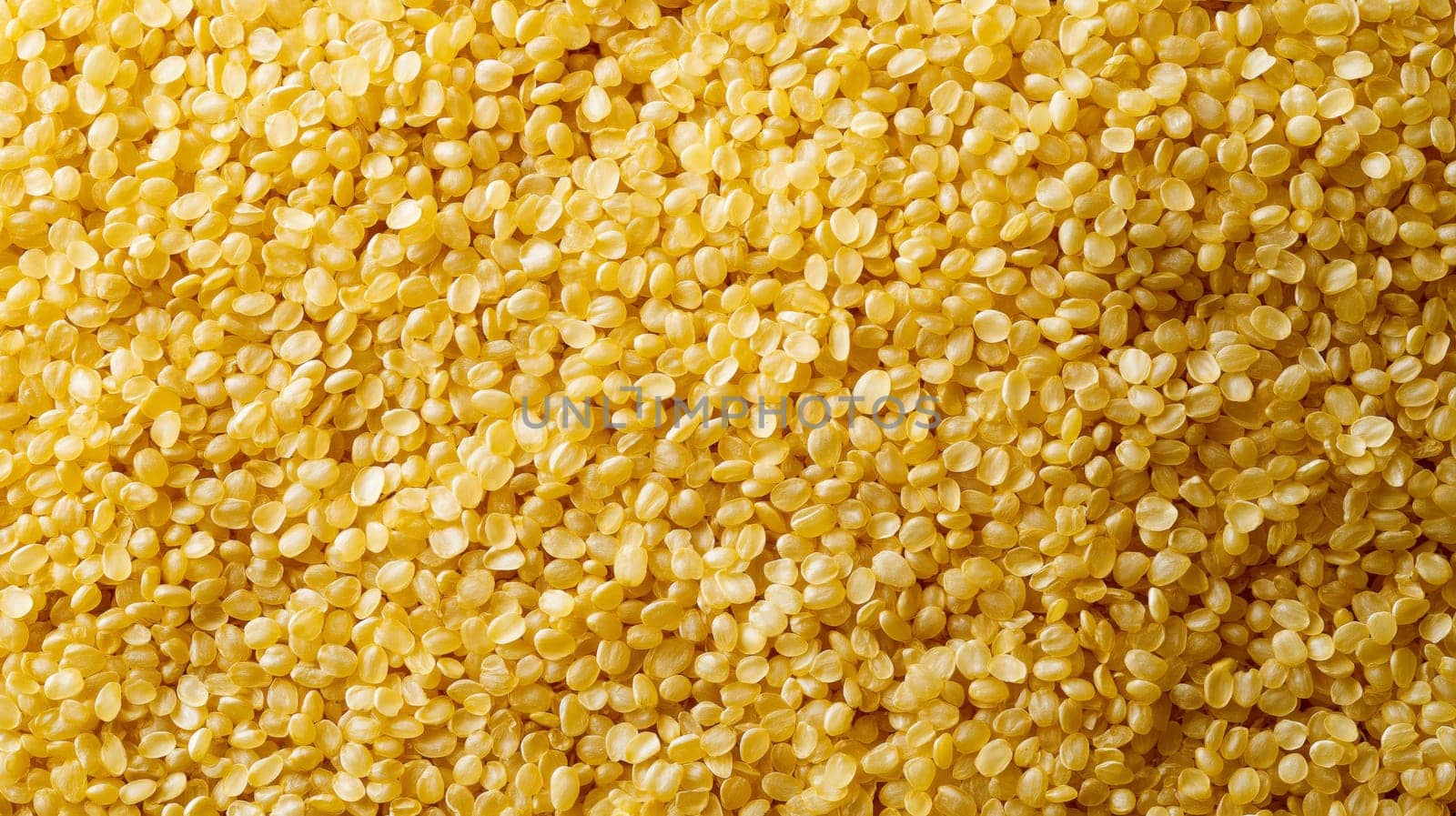 Close-up view of a dense background filled with golden raw bulgur grains, showcasing their texture. ideal for use in culinary presentations, food backdrops, or as a detailed texture for design projects.