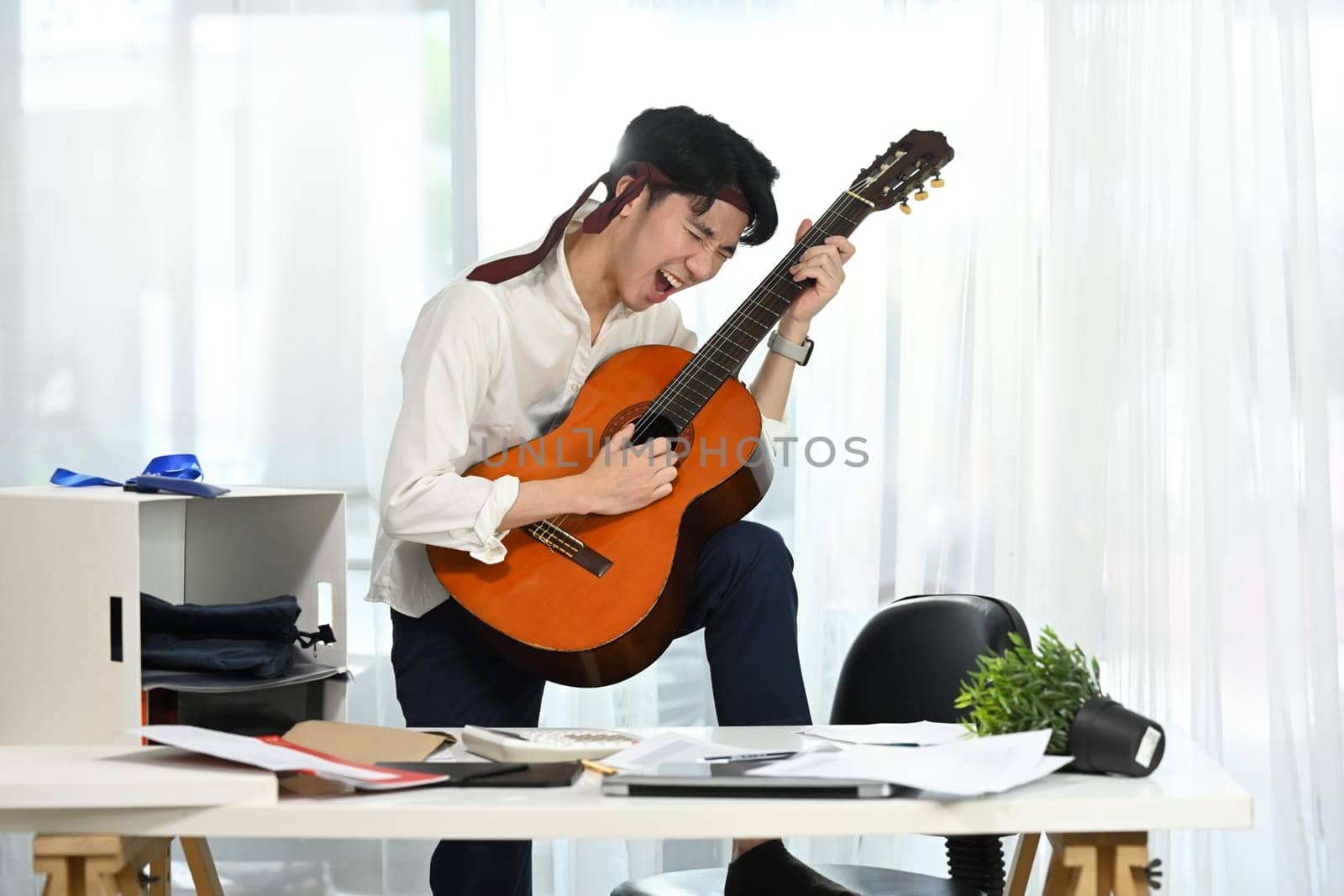 Joyful employee playing guitar during break at the workplace.