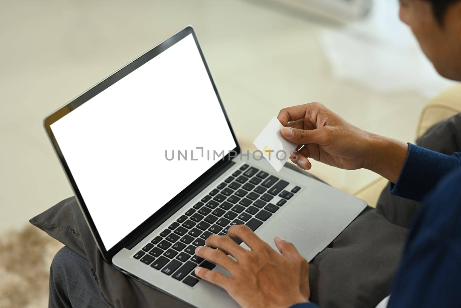 Young adult man holding a credit card and using laptop for shopping online.