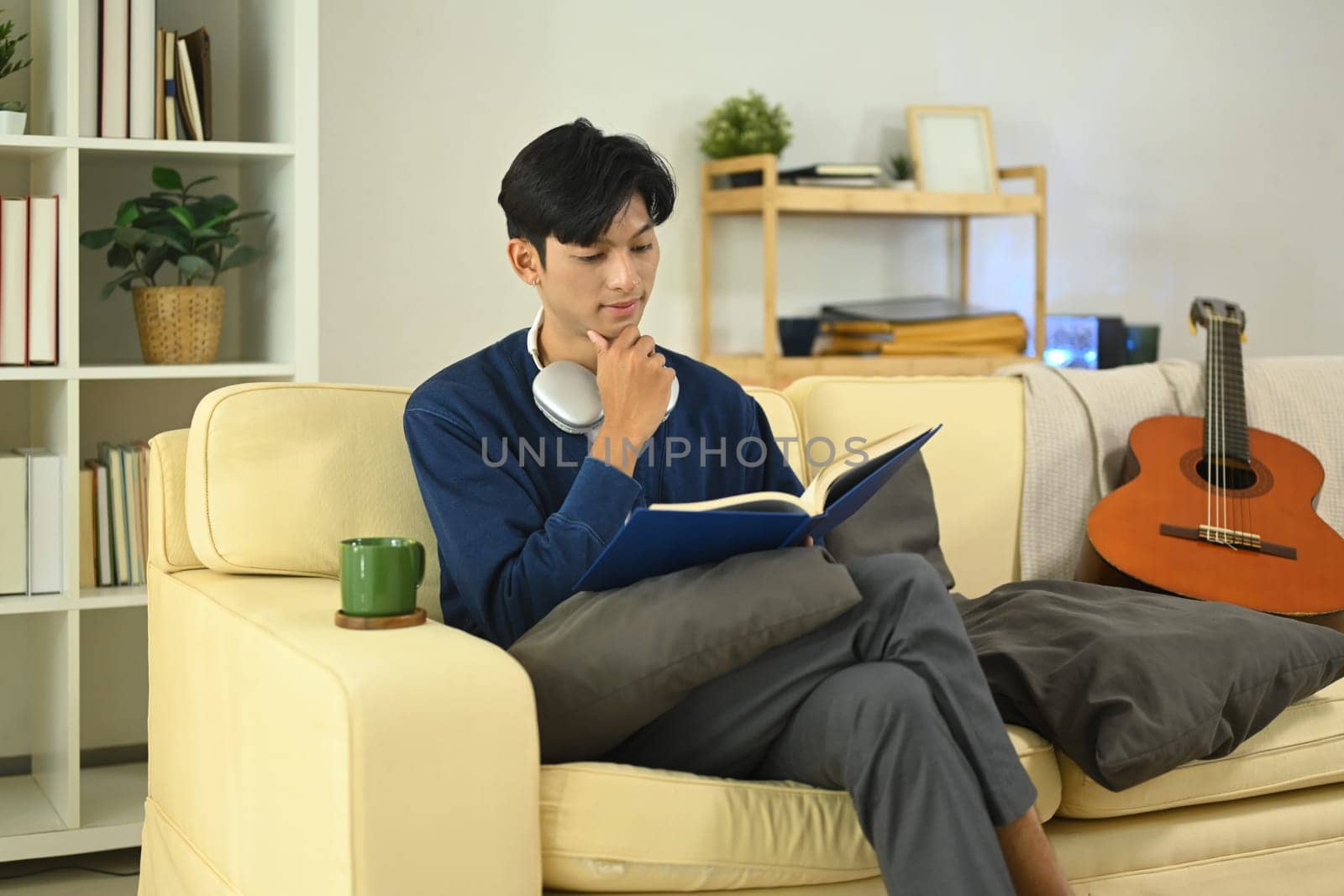 Young asian man reading the book and enjoying his free time at home.