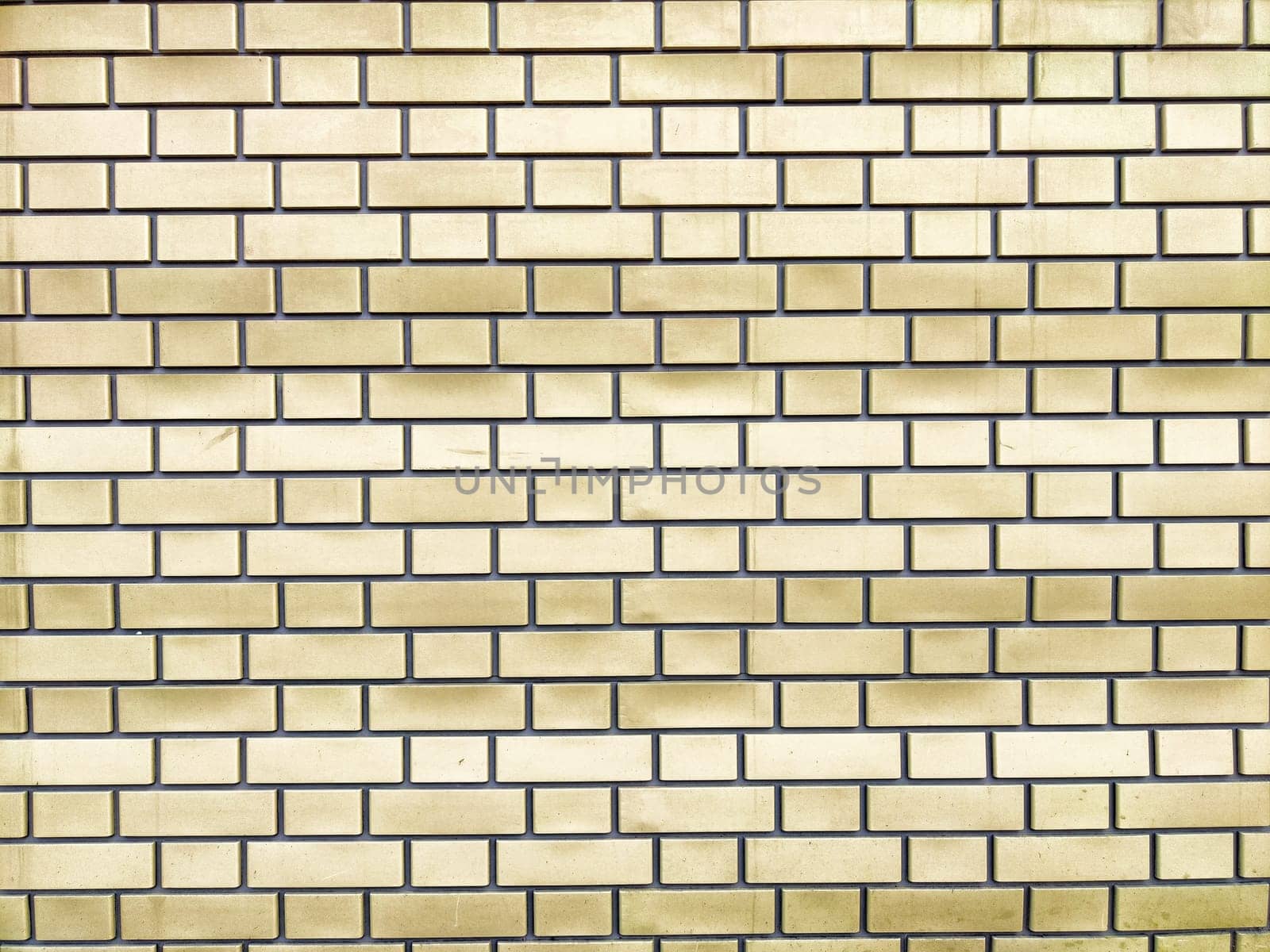 A close-up view of a yellow brick wall with a structured layout and even spacing between the bricks.
