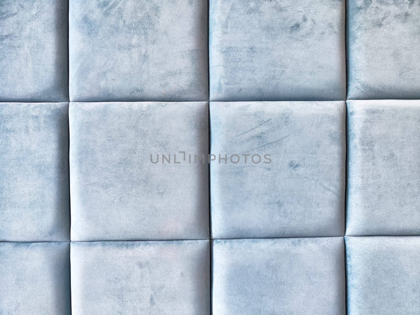 A modern living area features soft blue upholstered wall panels, providing a tranquil and stylish atmosphere for relaxation.
