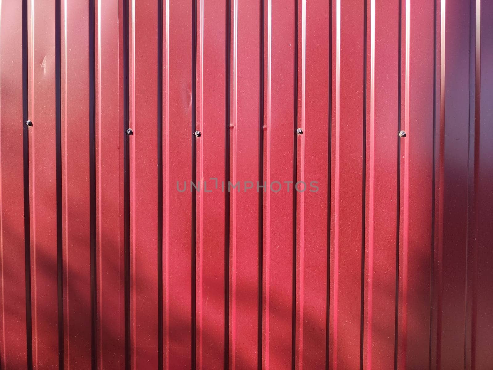 A vibrant red textured wall featuring vertical metal panels, creating a modern backdrop with ample copy space for branding.