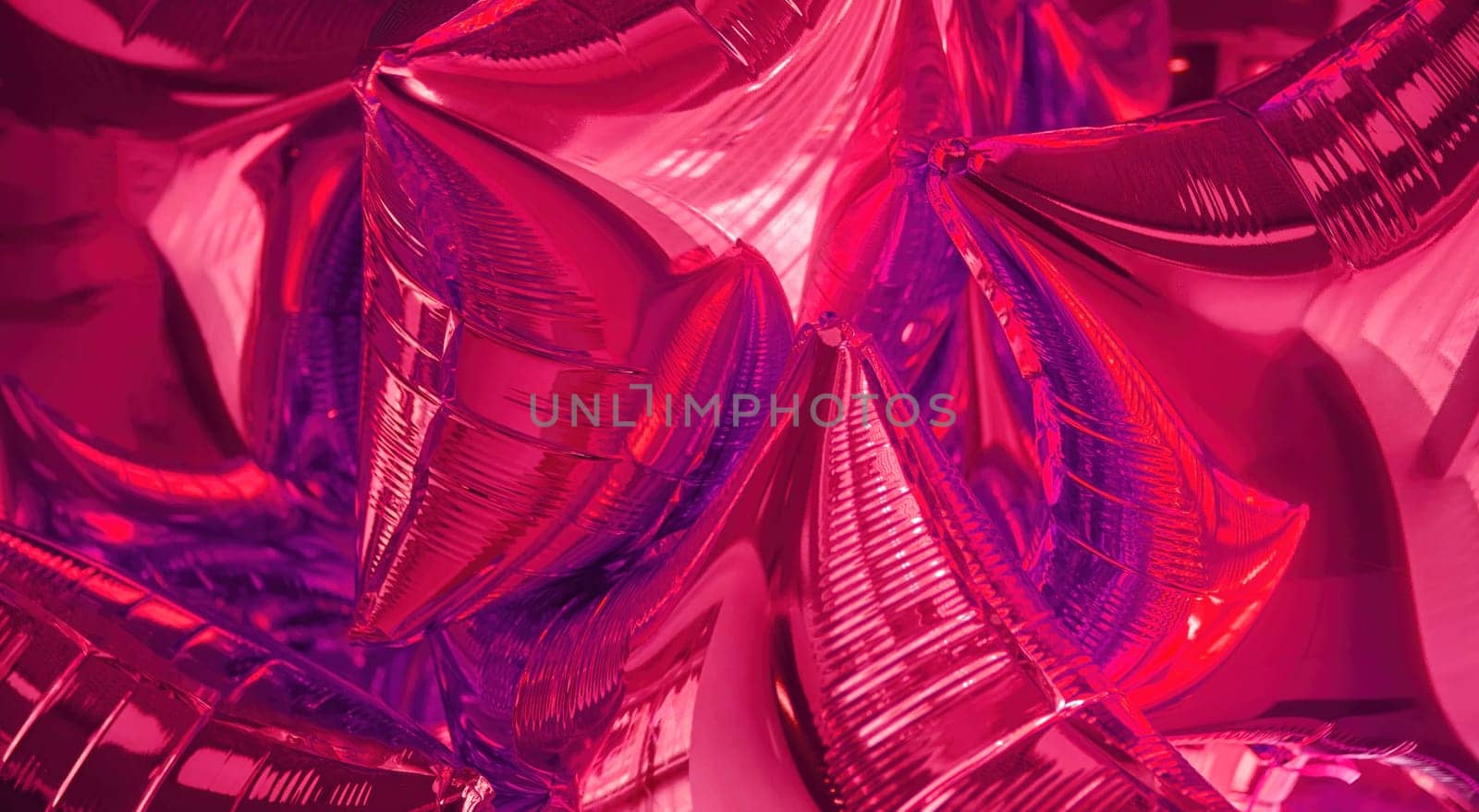 A collection of shiny pink metallic balloons fills the frame, creating a festive atmosphere ideal for celebrations, parties, or special occasions, reflecting light beautifully.