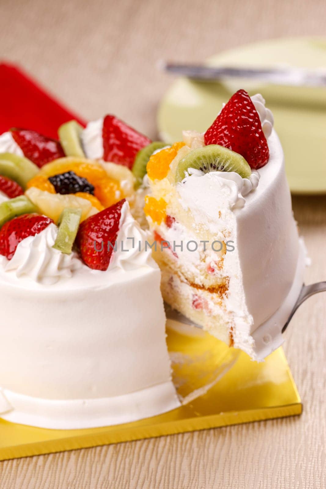 Lifting a slice of white cake topped with fresh fruit.