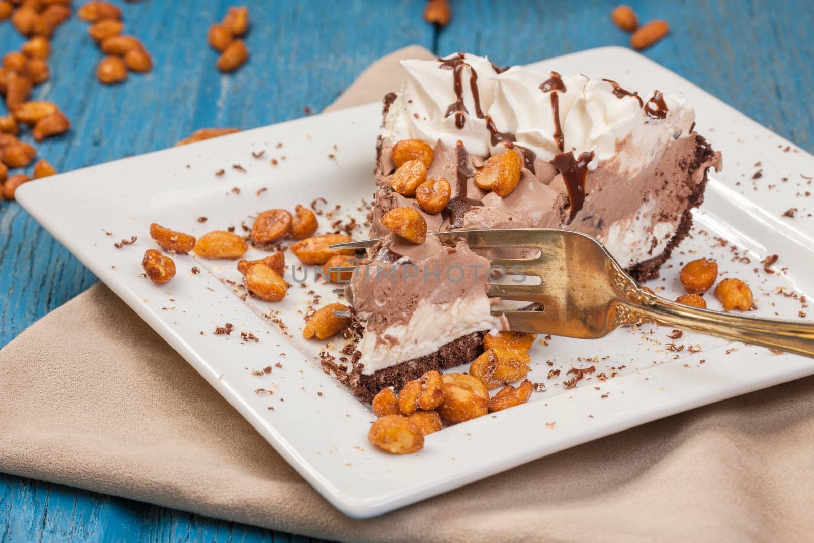 A studio image of a slice of ice cream pie along with peanuts.