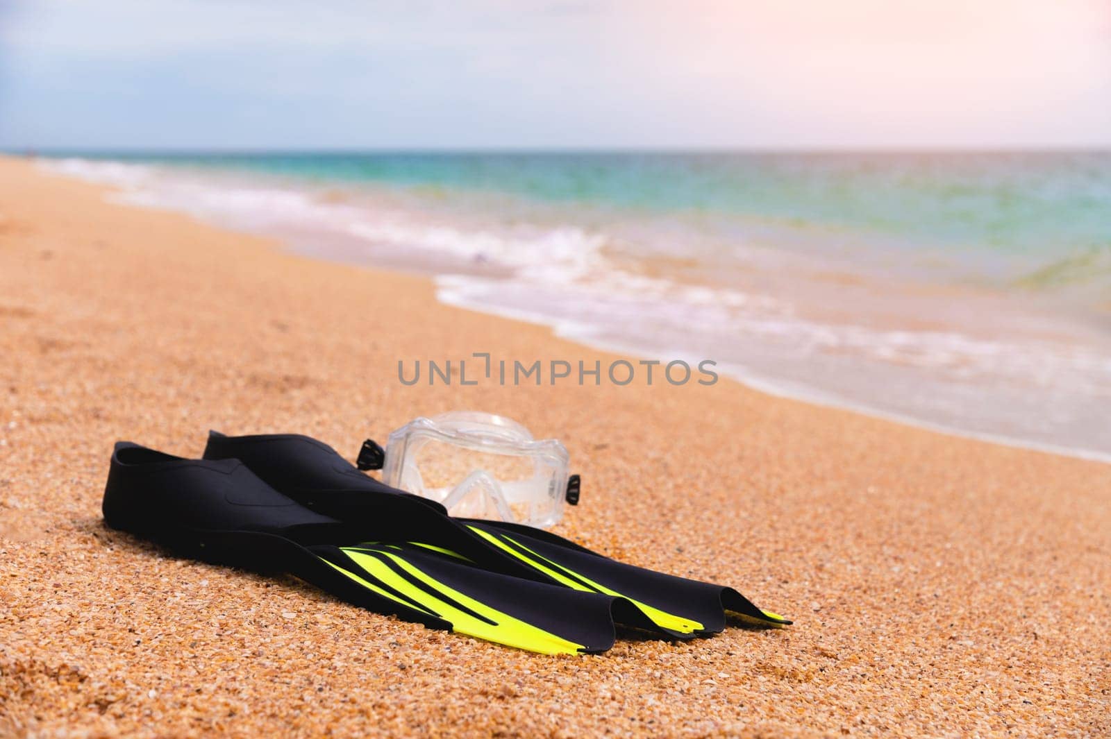 Snorkeling mask and fins on a tropical beach. Black fins on the seashore close-up.